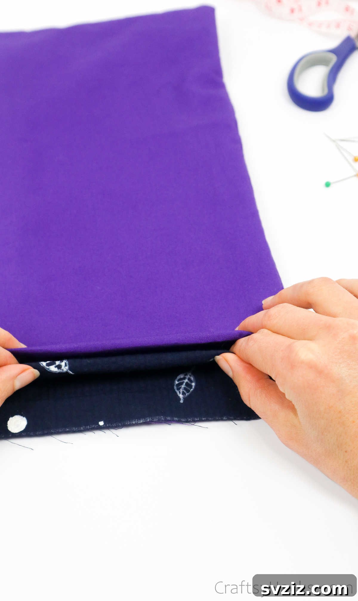 Carefully folding the fabric to ensure an even and aligned rim for the tote bag opening