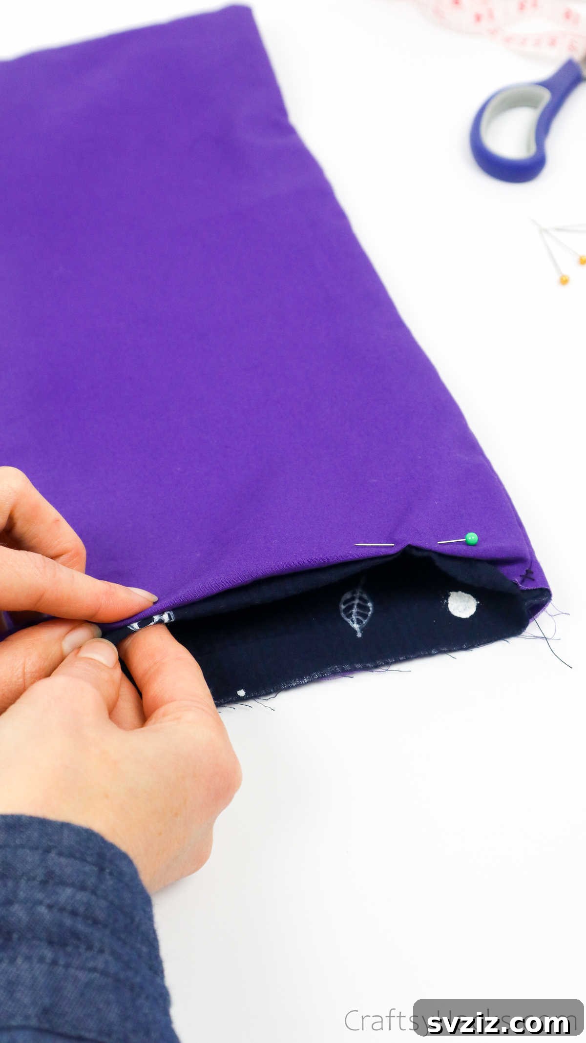 Pinning the folded fabric edges to secure the neat hem of the tote bag opening