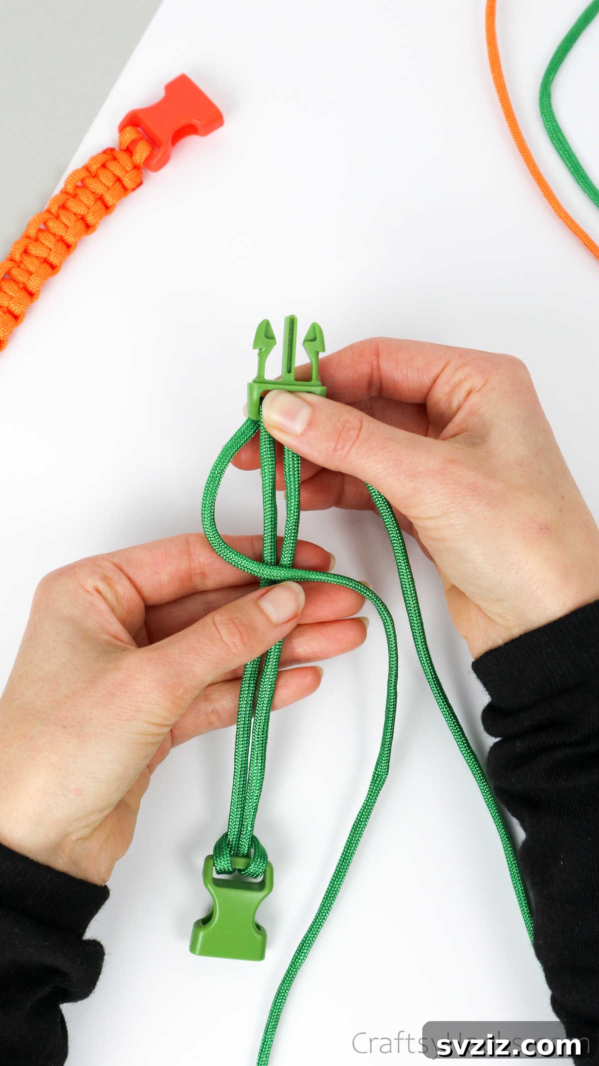 The left paracord strand is looped over the two central strands, forming the initial 'P' shape of the knot.