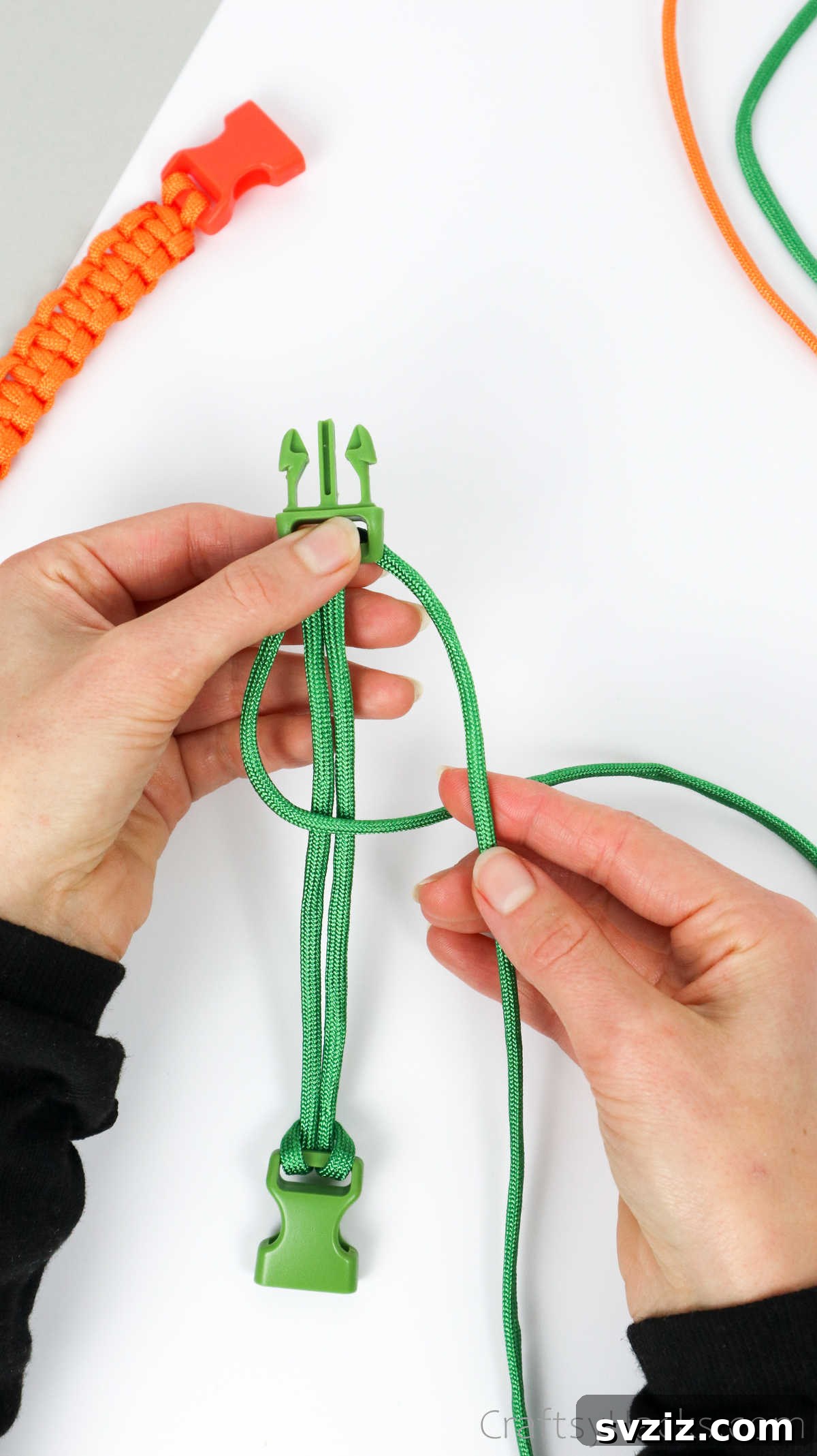 The right paracord strand is passed over the left, then under the central cords, and through the left loop.