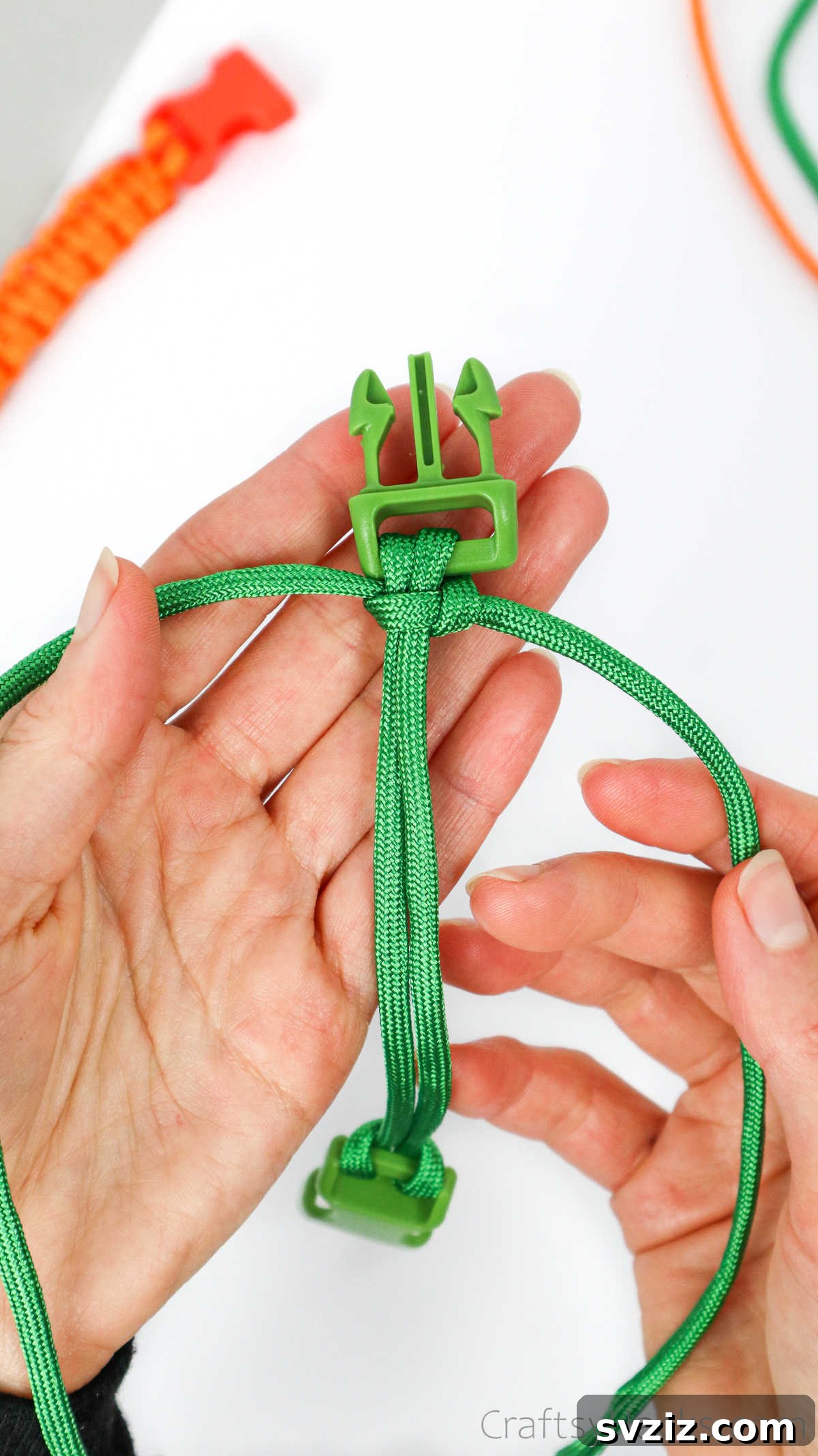 The first half of the square knot is tightened and pushed up against the buckle, forming a clean knot.