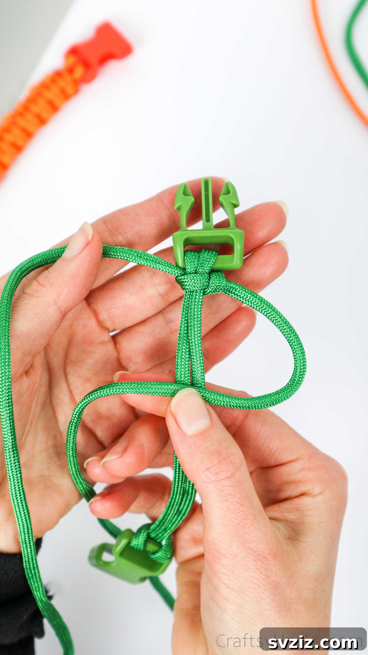 The right paracord strand is now looped over the central cords, starting the second half of the square knot.
