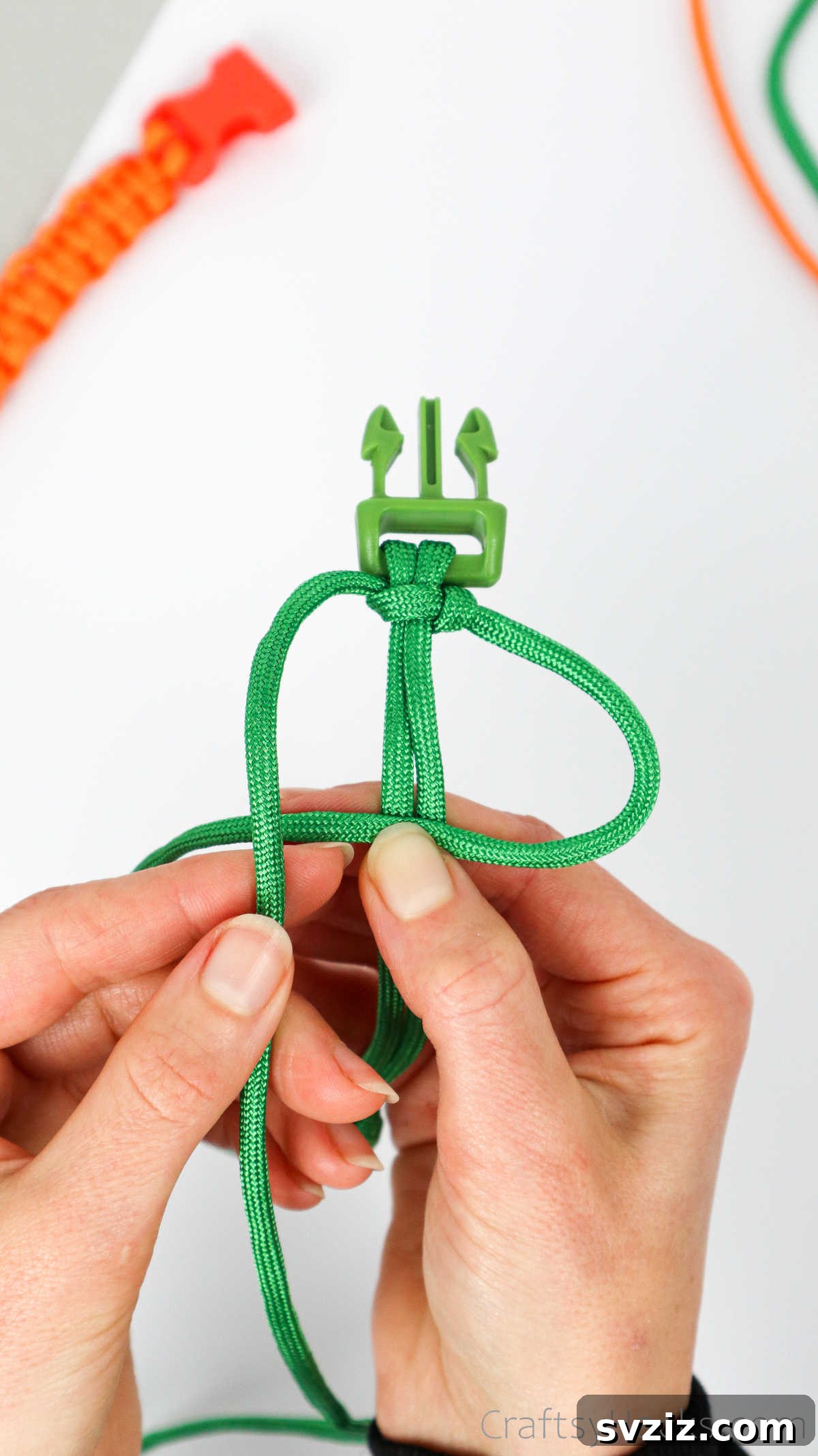 The left paracord strand is passed over the right, then under the central cords, and through the right loop.