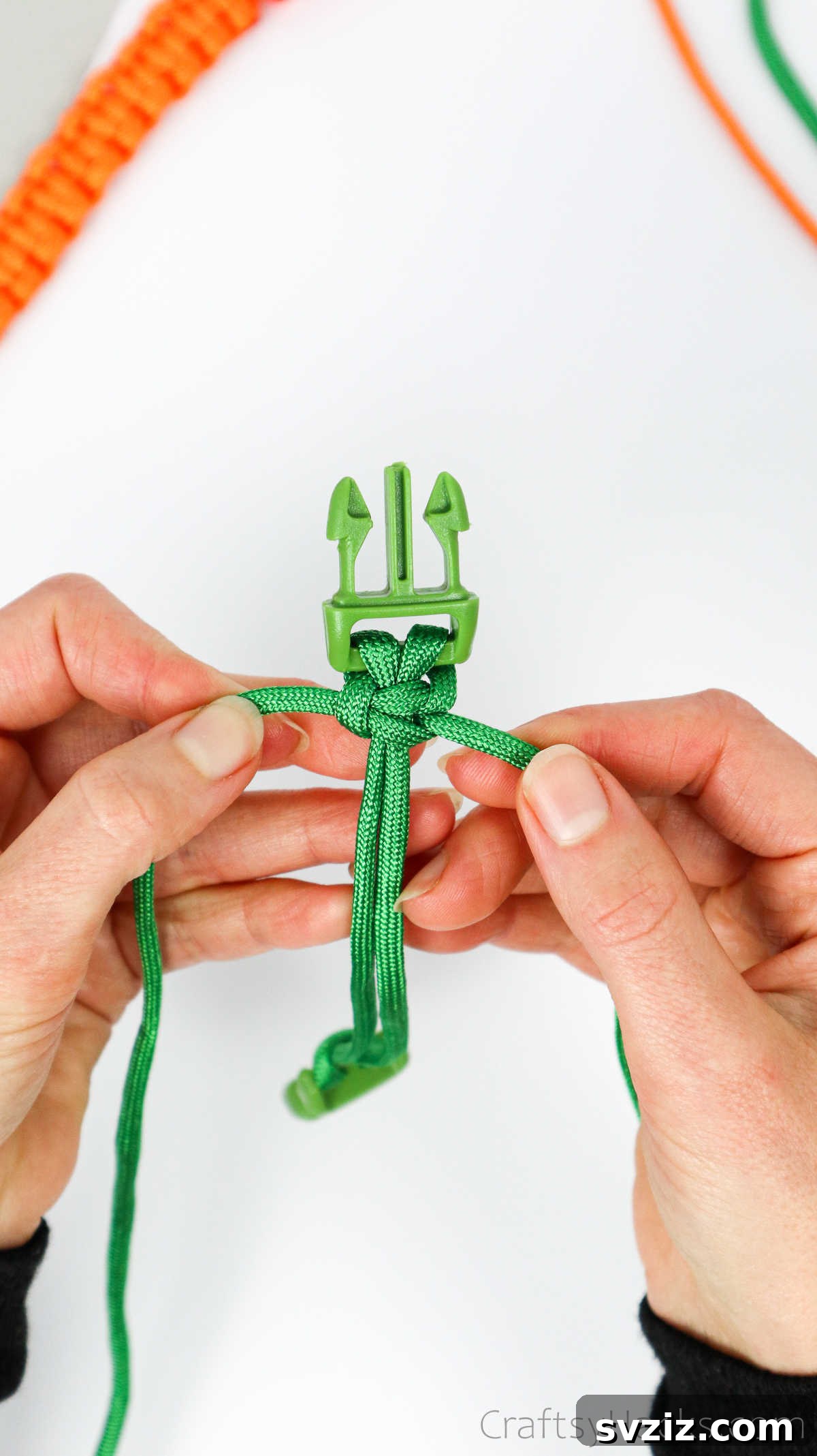 A completed square knot, securely tightened and sitting flush against the previous knot on the paracord.