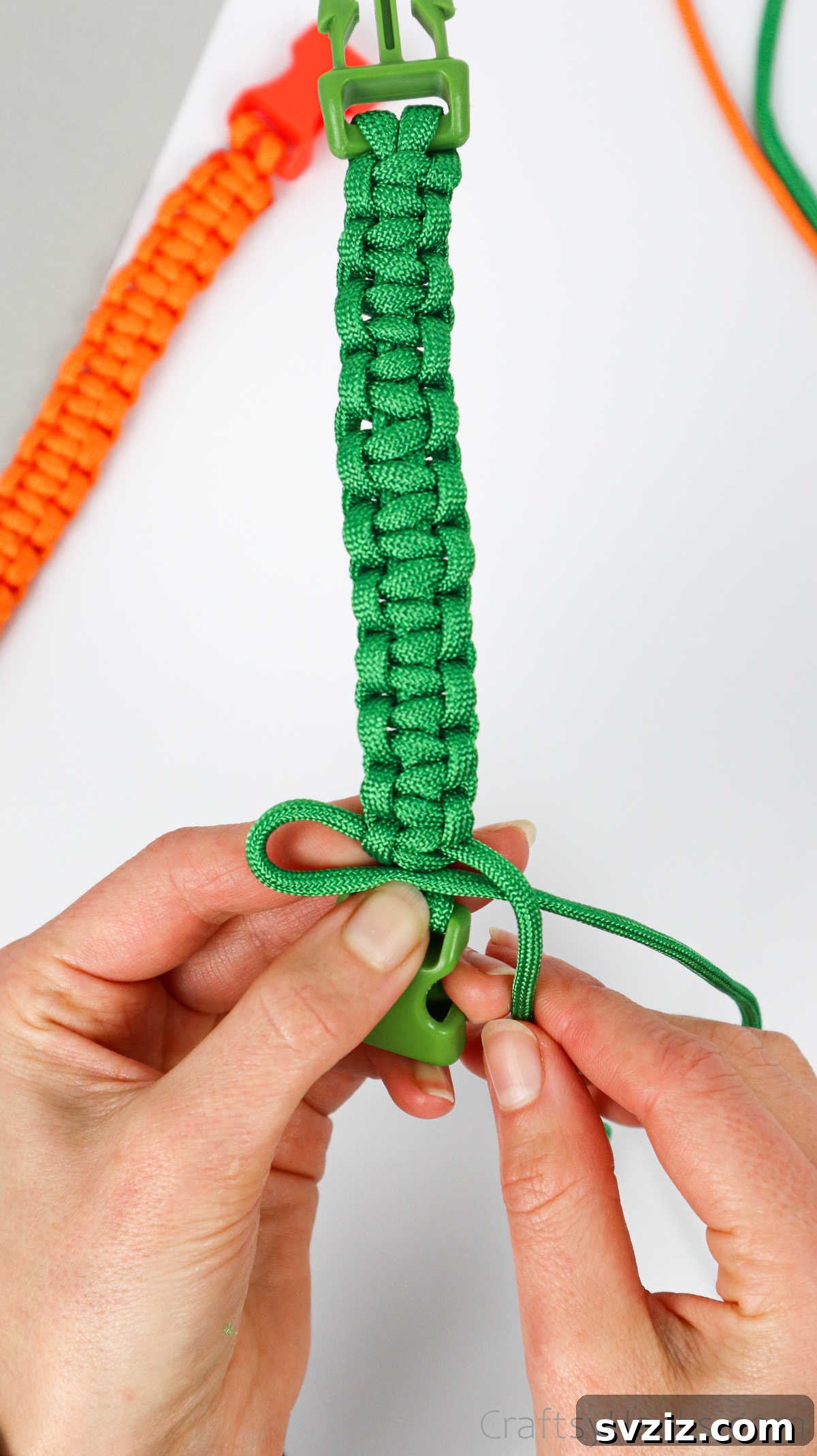 The final square knot being tied right at the edge of the second buckle half, completing the weave.