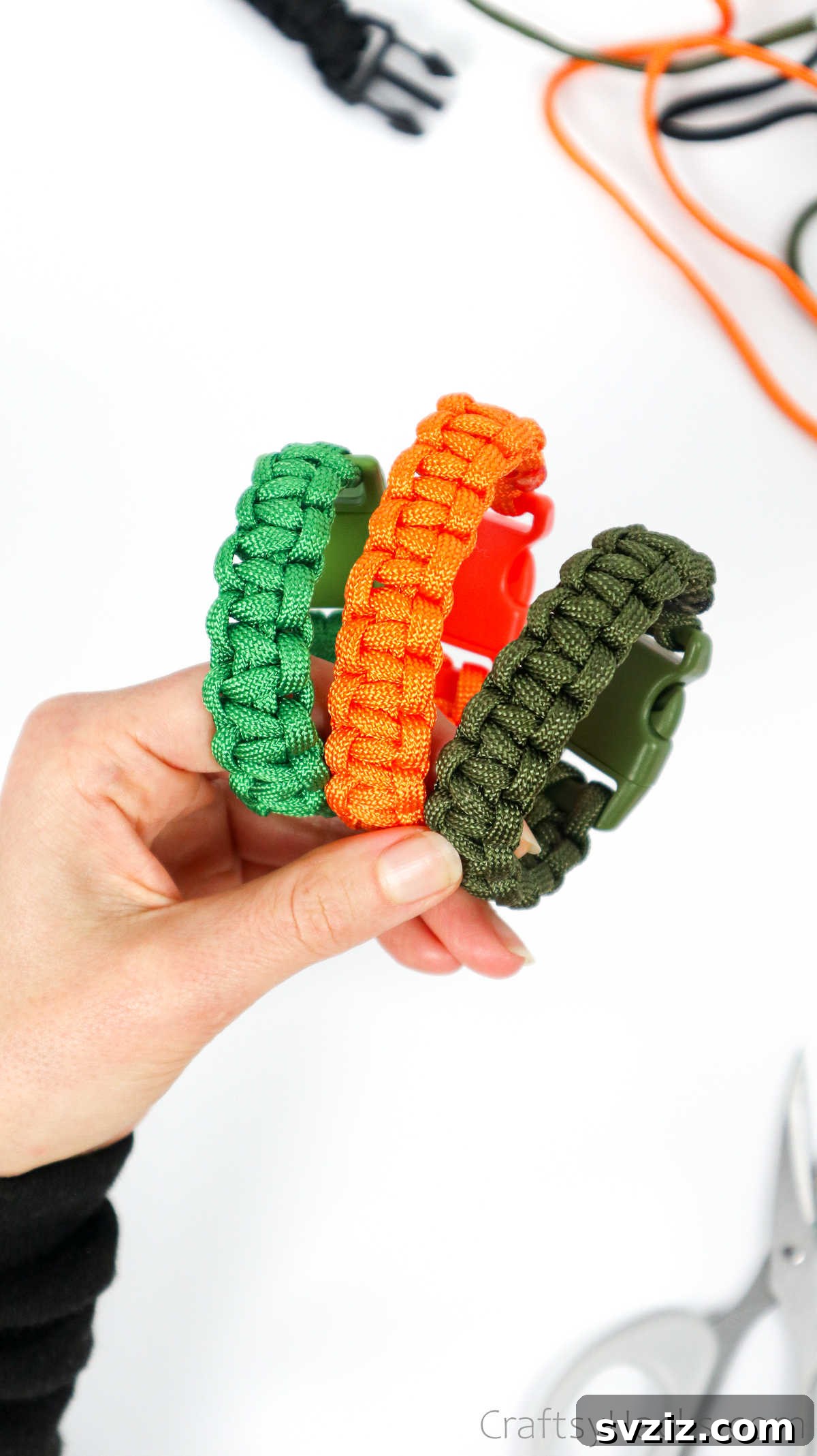 Two hands gently holding a trio of finished paracord bracelets, highlighting their texture and design.