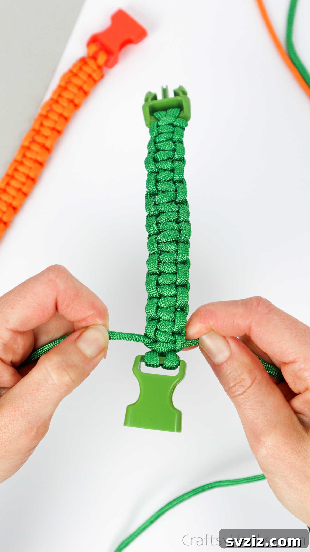 The final square knot is securely tightened against the buckle, ready for the excess cord to be trimmed.
