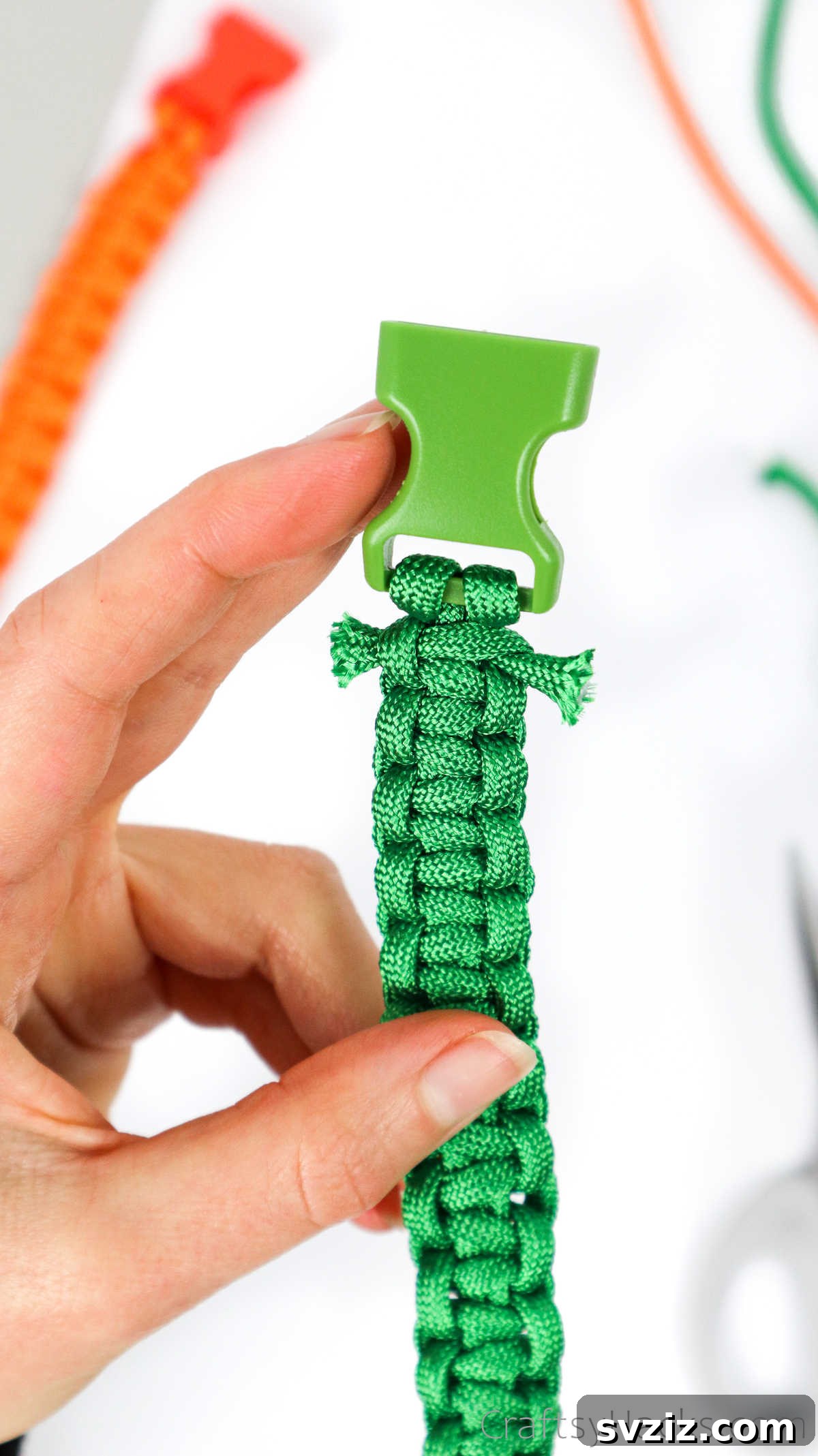 A close-up of a completed paracord bracelet, held by hand, showing the woven texture and buckle.
