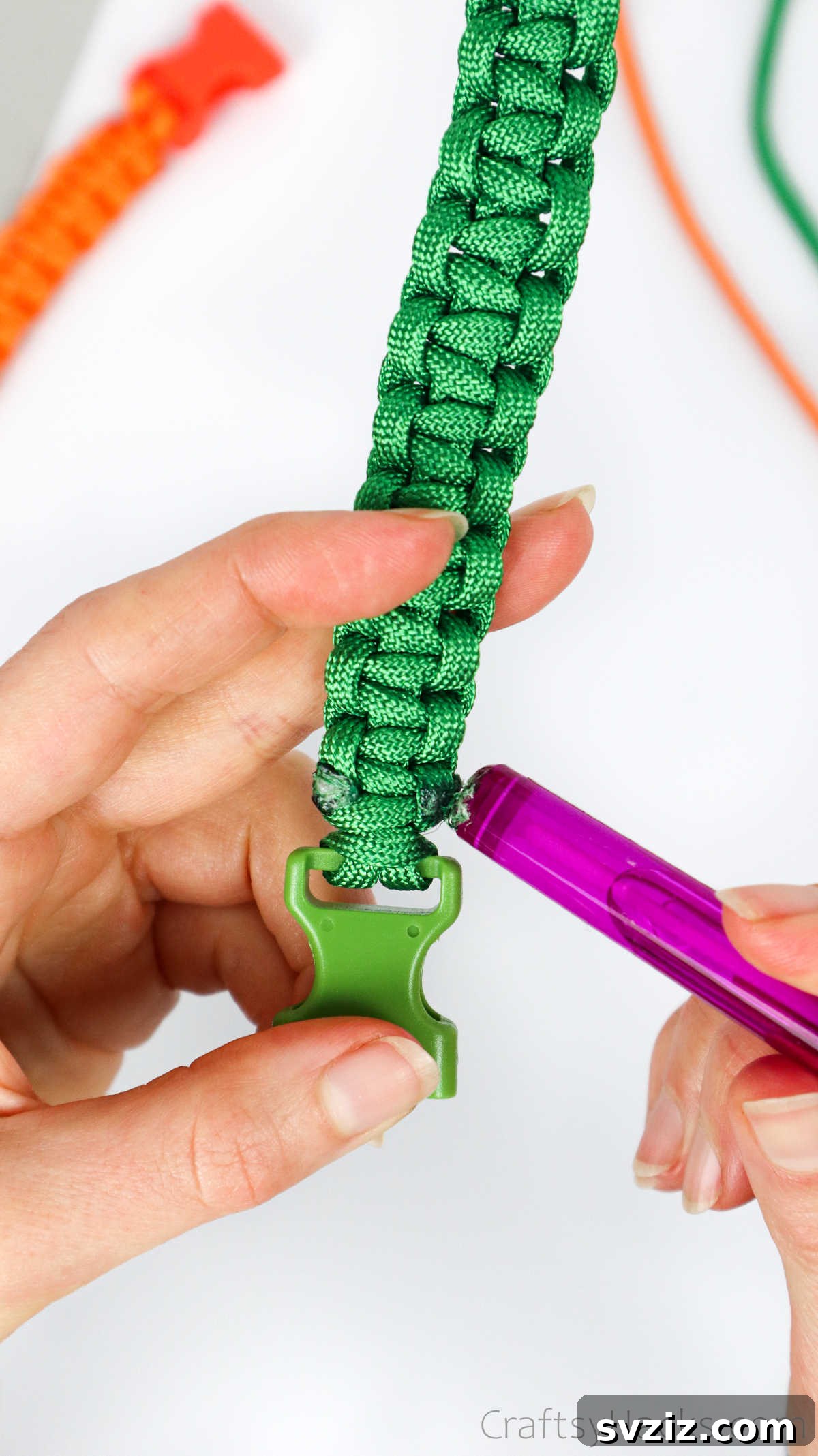 A hand carefully flattening the melted paracord ends against the bracelet, creating a smooth finish.
