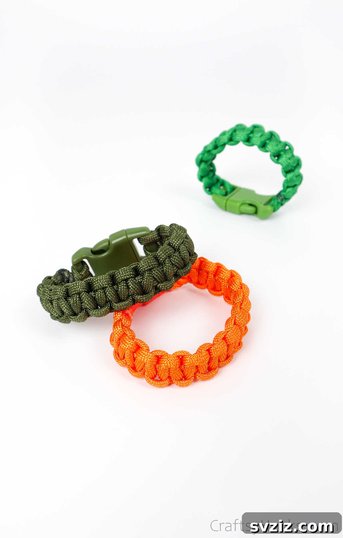 A collection of three vibrant paracord bracelets, featuring green and orange, showcasing detailed weaving.