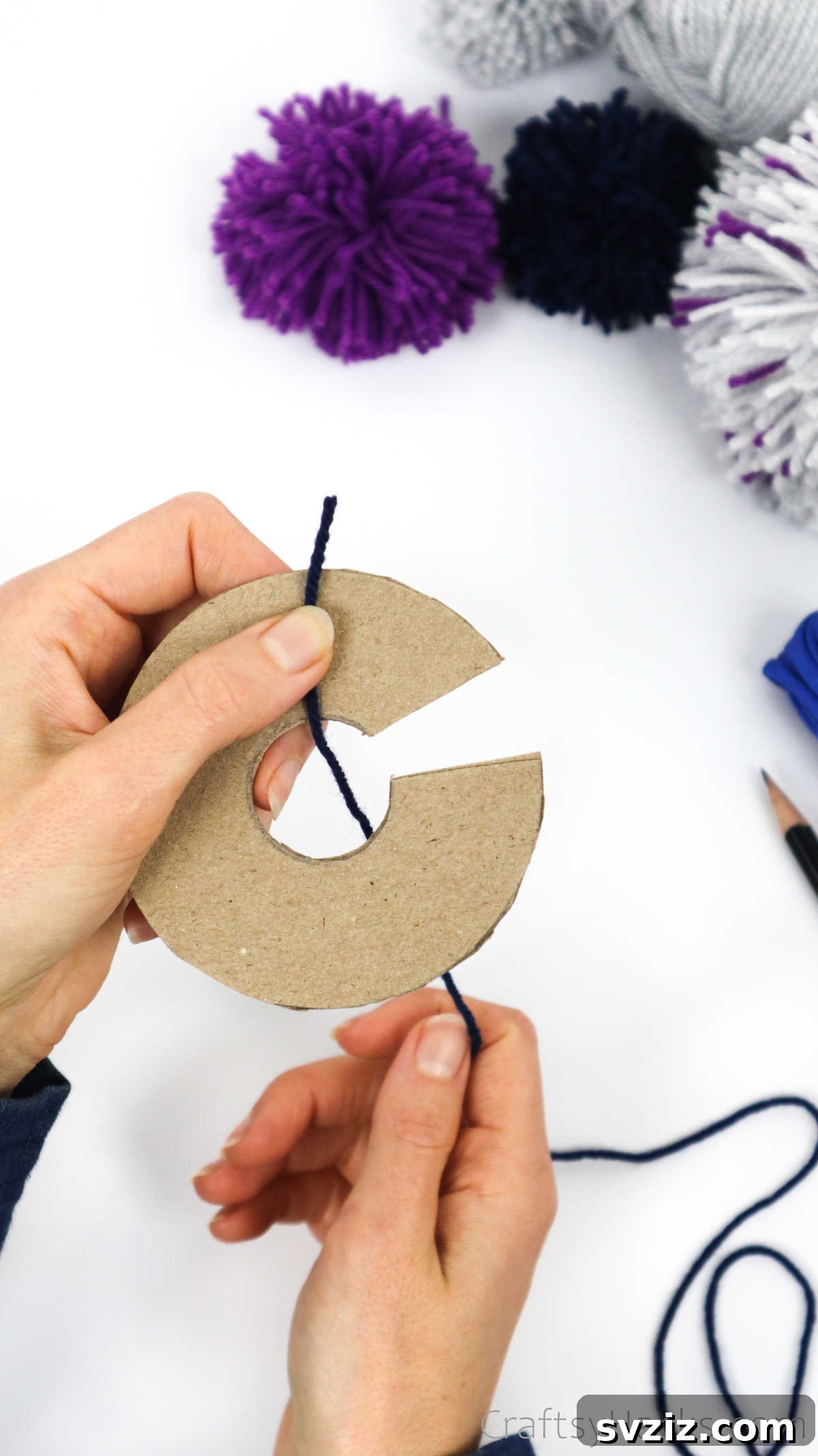 Pulling yarn through the central hole of the cardboard disks