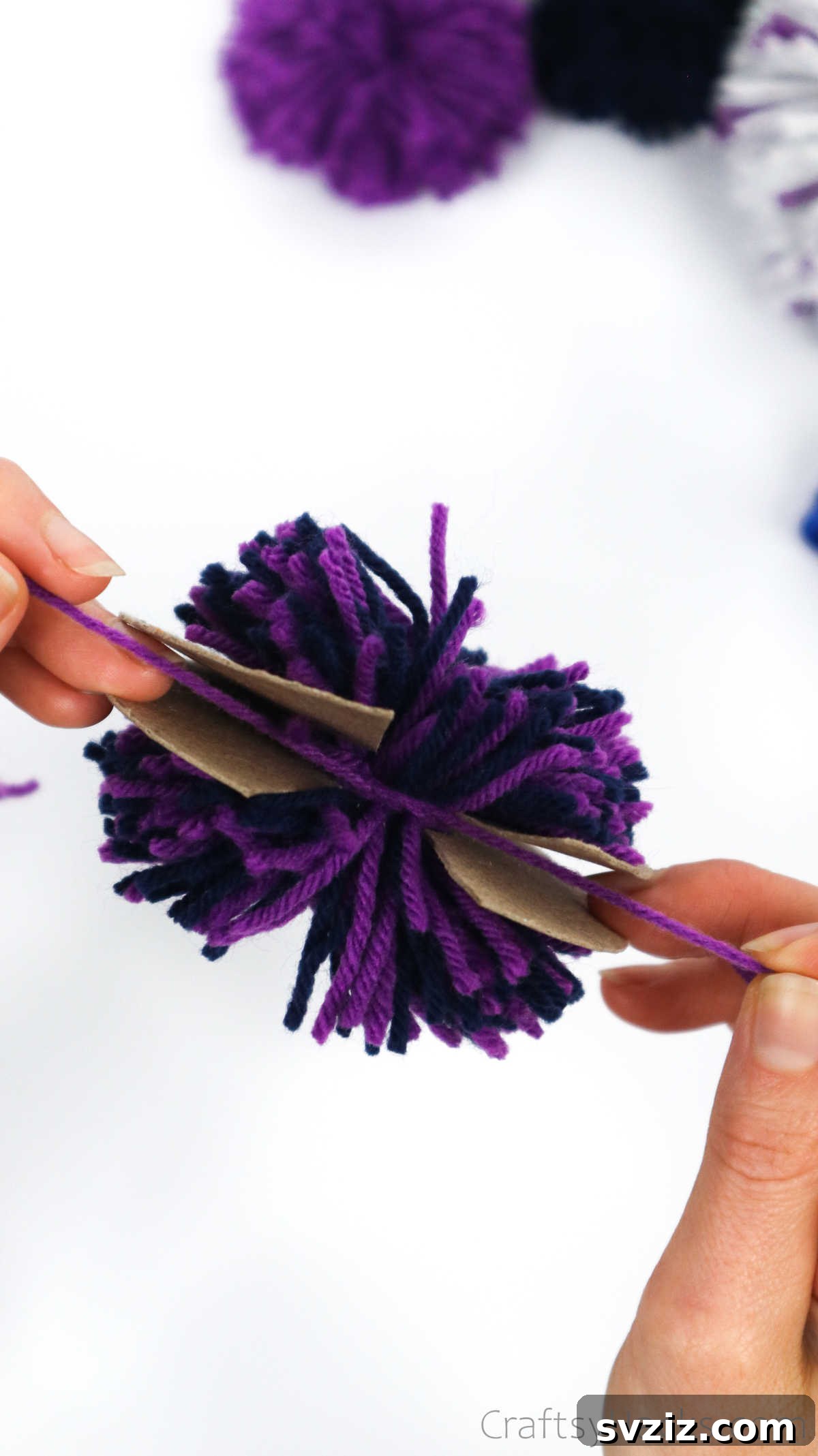 Tightening the knot to secure the yarn pom pom