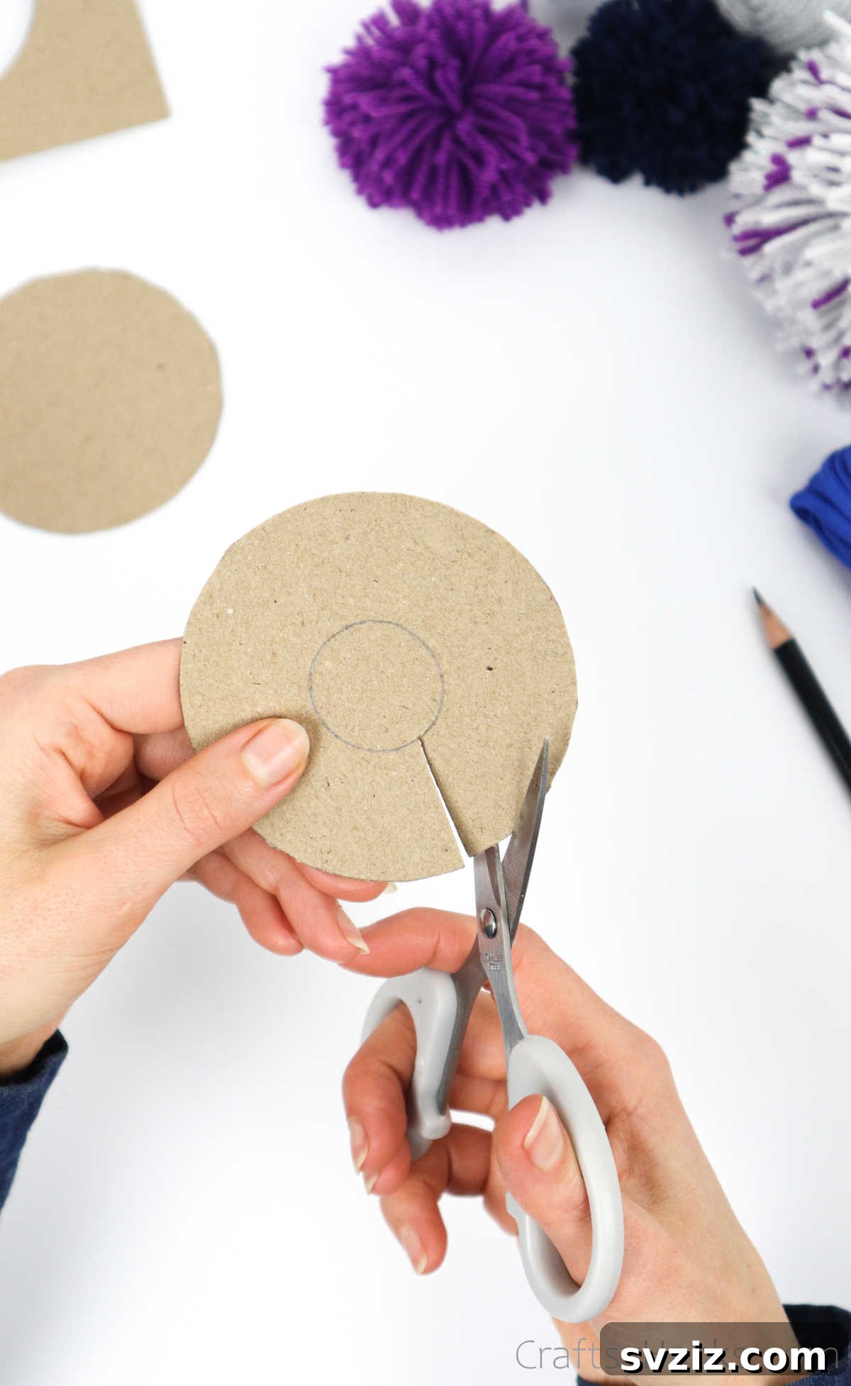 Cutting out the inner circle from a cardboard disk to create a donut shape
