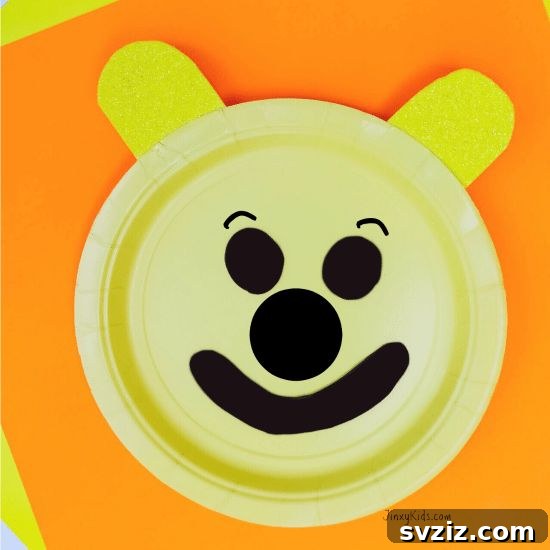 Crafting Smiles: Paper Plate Fun for Kids 19 Cheerful Winnie the Pooh paper plate craft with his smiling face and tiny red shirt detail.