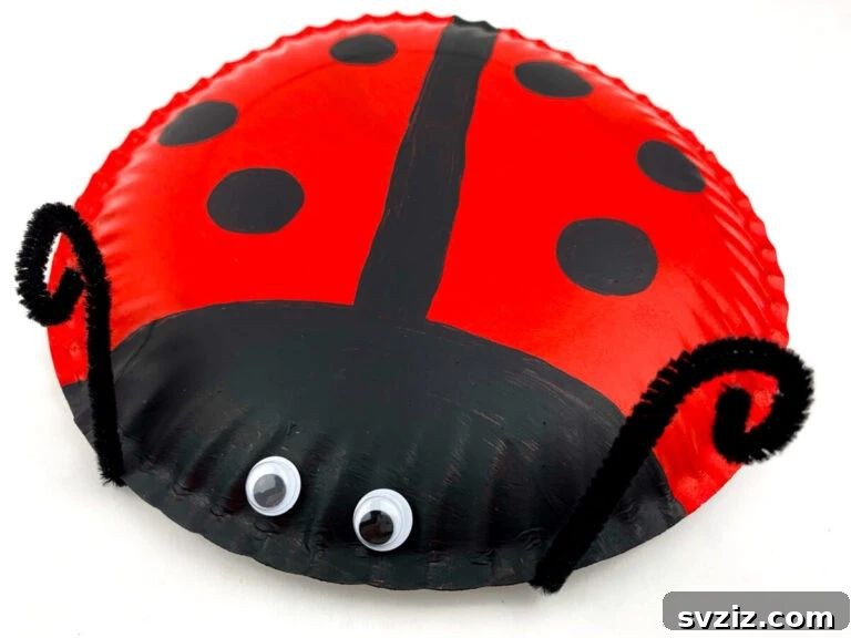 Crafting Smiles: Paper Plate Fun for Kids 22 Three-dimensional paper plate ladybug craft with black spots and googly eyes, standing out with its raised back.