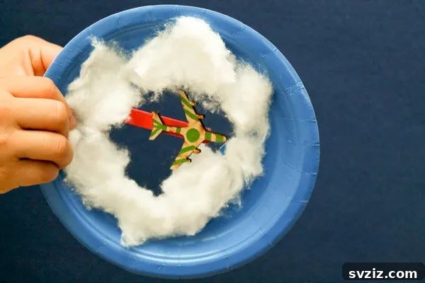 Crafting Smiles: Paper Plate Fun for Kids 32 Creative paper plate craft depicting a plane flying through fluffy cotton clouds in a blue sky.