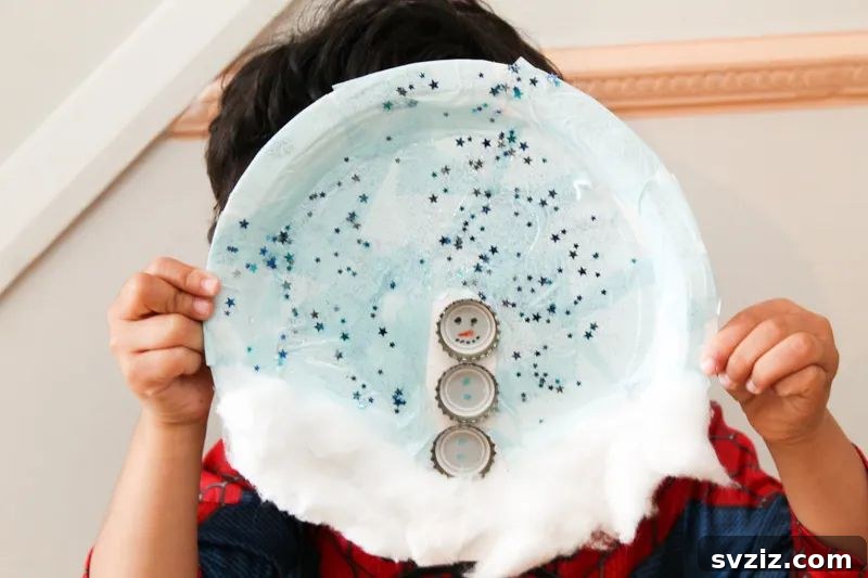 Crafting Smiles: Paper Plate Fun for Kids 35 Whimsical paper plate snowman scene with a smiling snowman, tiny birds, and snow-covered trees.