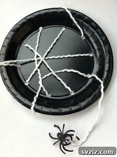 Crafting Smiles: Paper Plate Fun for Kids 41 Detailed paper plate spider web craft with white yarn woven through holes, featuring a plastic spider.