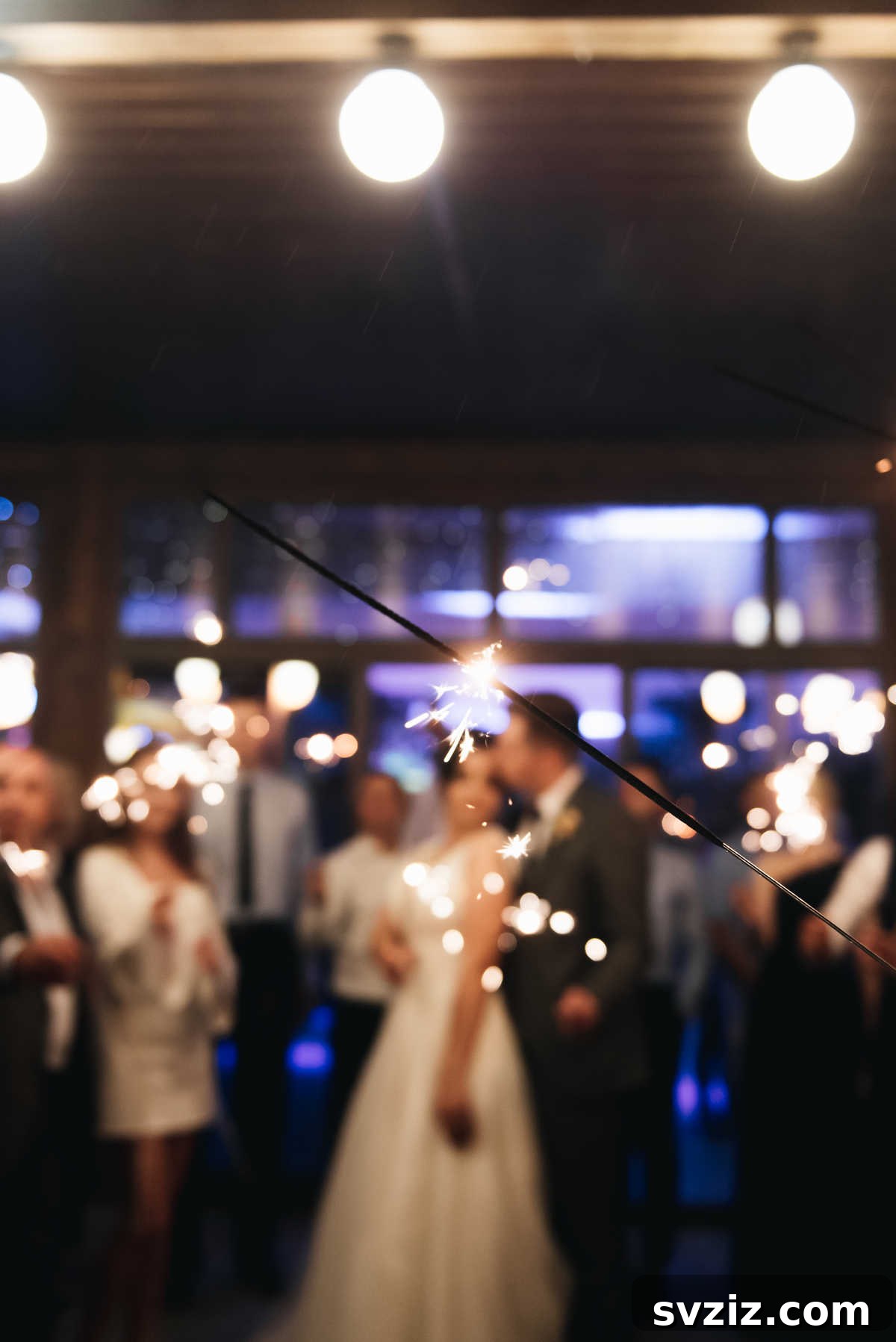 Guests holding sparklers as a couple walks through their illuminated pathway