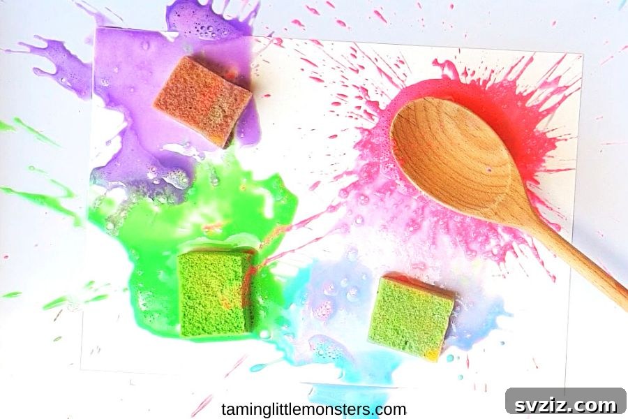 Children engaged in outdoor splat painting, using sponges and wooden spoons to create abstract art on paper.
