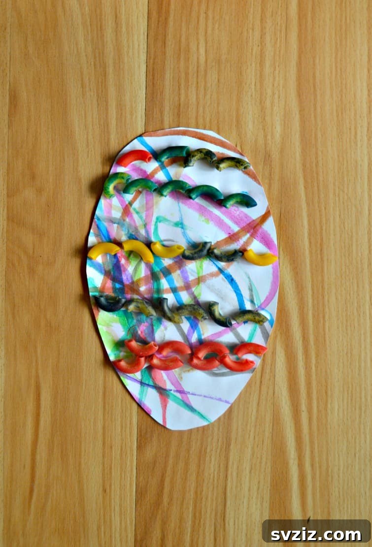 A colorful Easter egg craft decorated with painted pasta, a sensory and creative activity for toddlers.