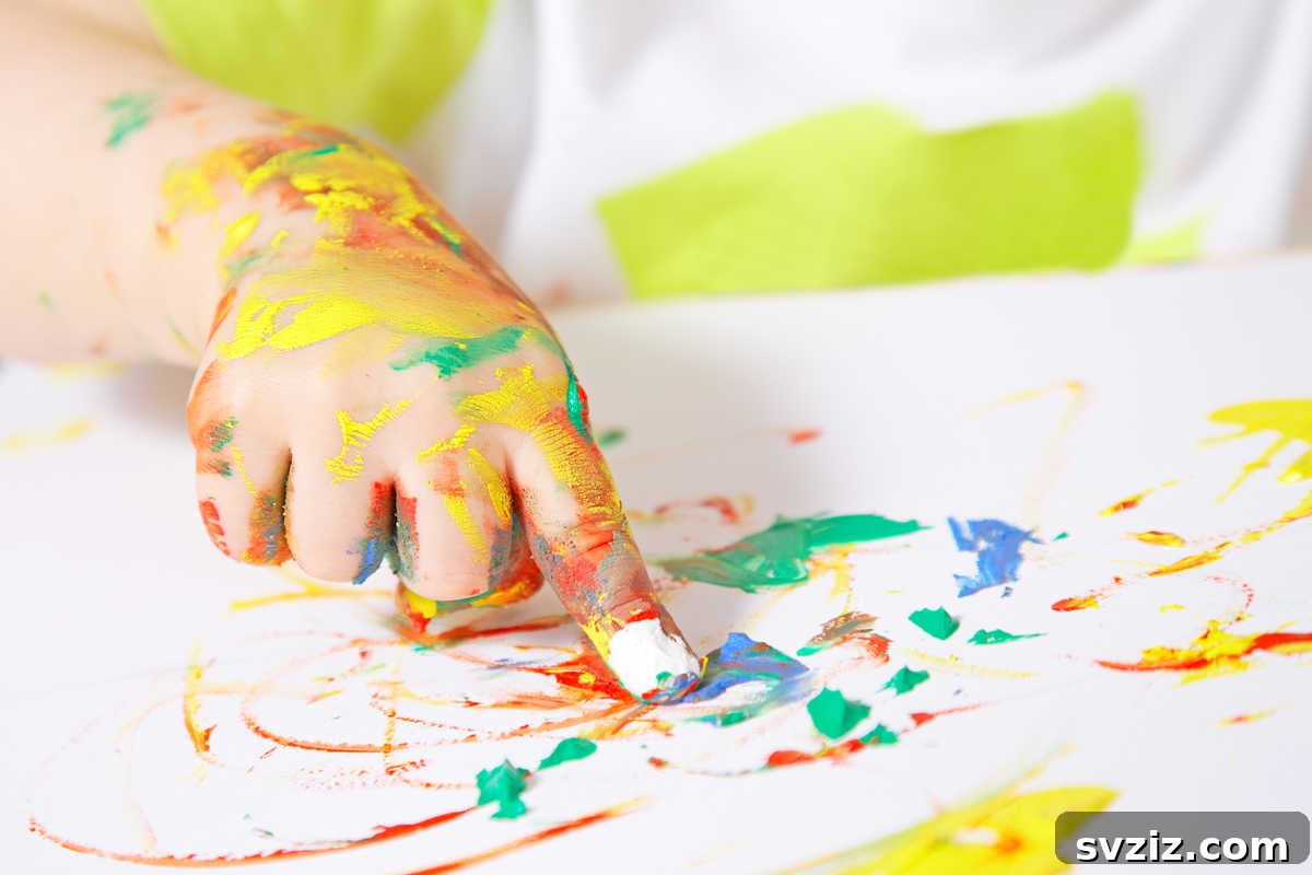 41 Creative Play Ideas for Two-Year-Olds 4 A toddler happily creating art with finger paints, showcasing messy play.