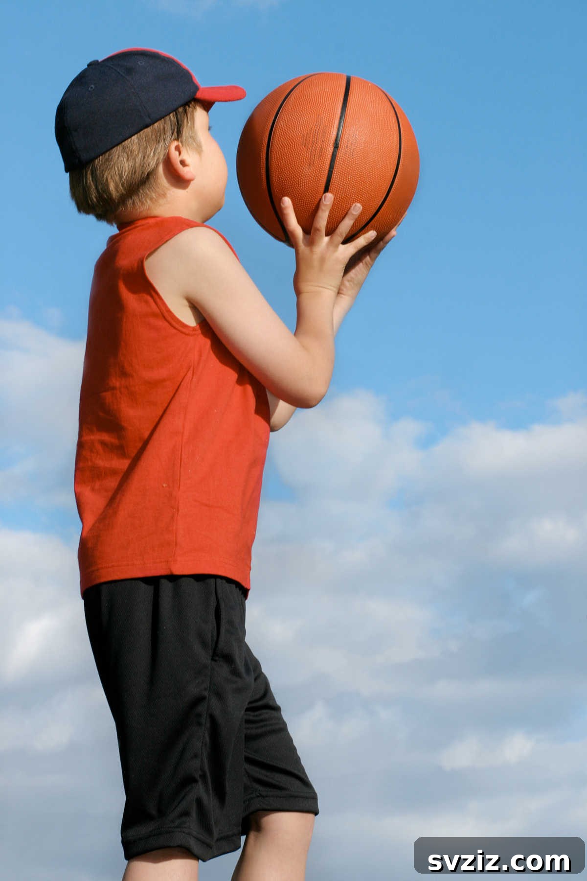 Boy shooting a basketball at a hoop in an outdoor court, an active and skill-building game.