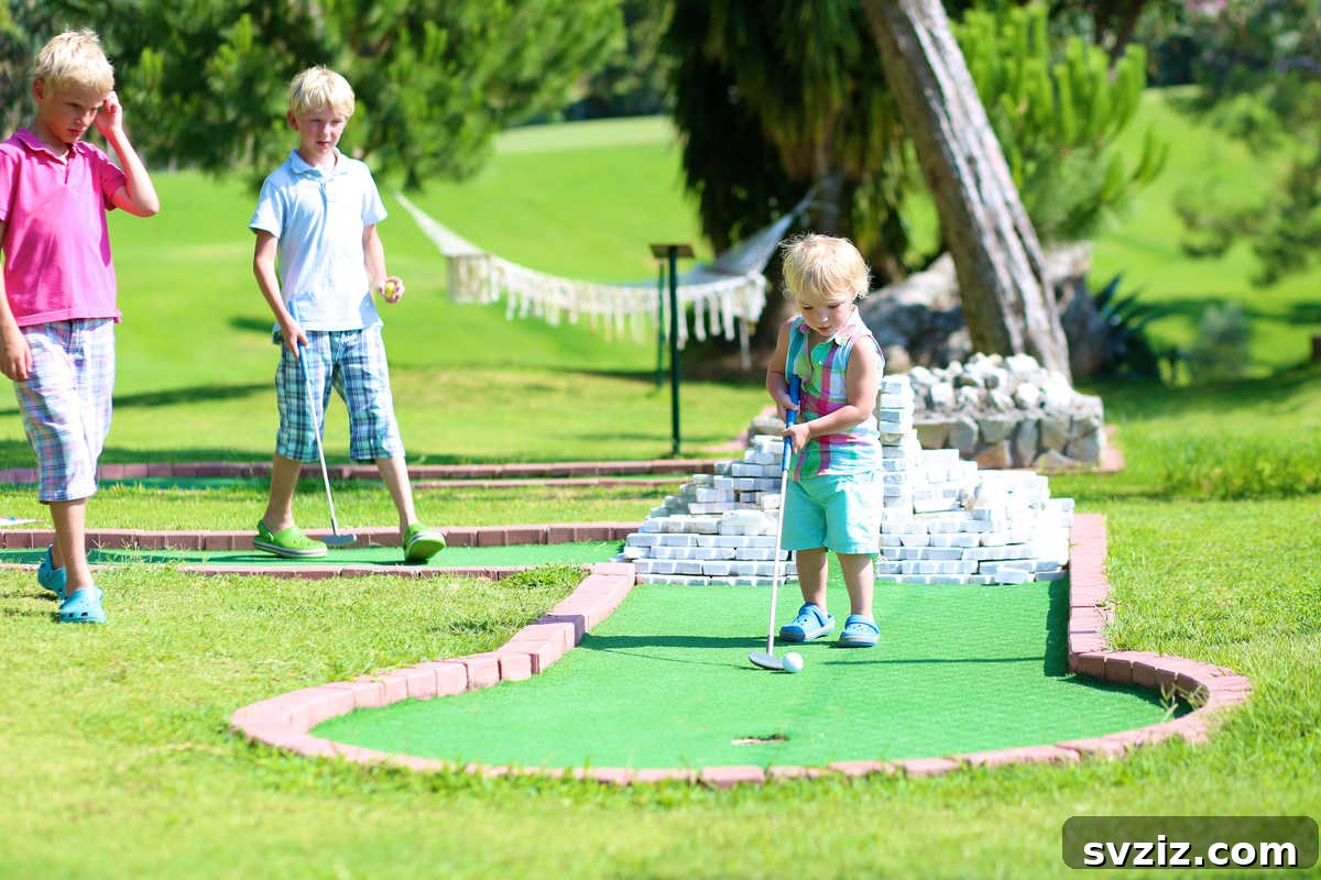 Boy focused on putting at a colorful mini-golf course, developing hand-eye coordination outdoors.