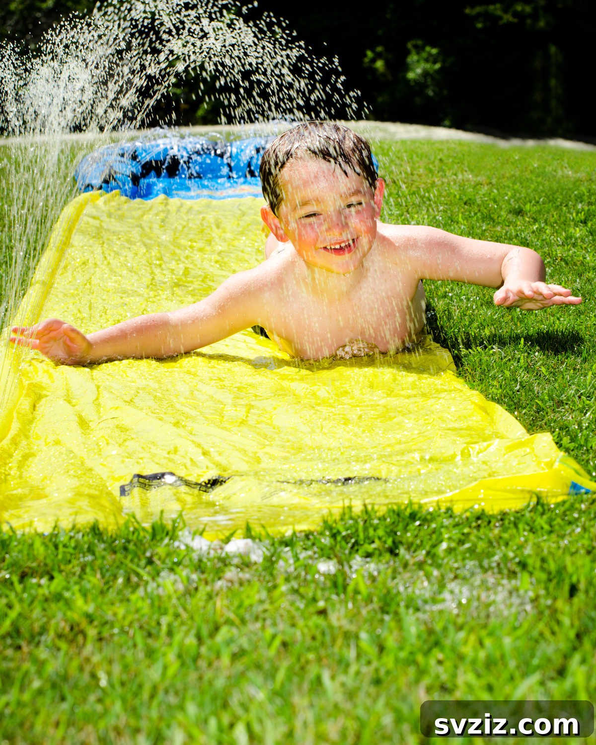 Kids joyfully sliding down a backyard Slip 'n Slide on a sunny day, a perfect summer outdoor activity.