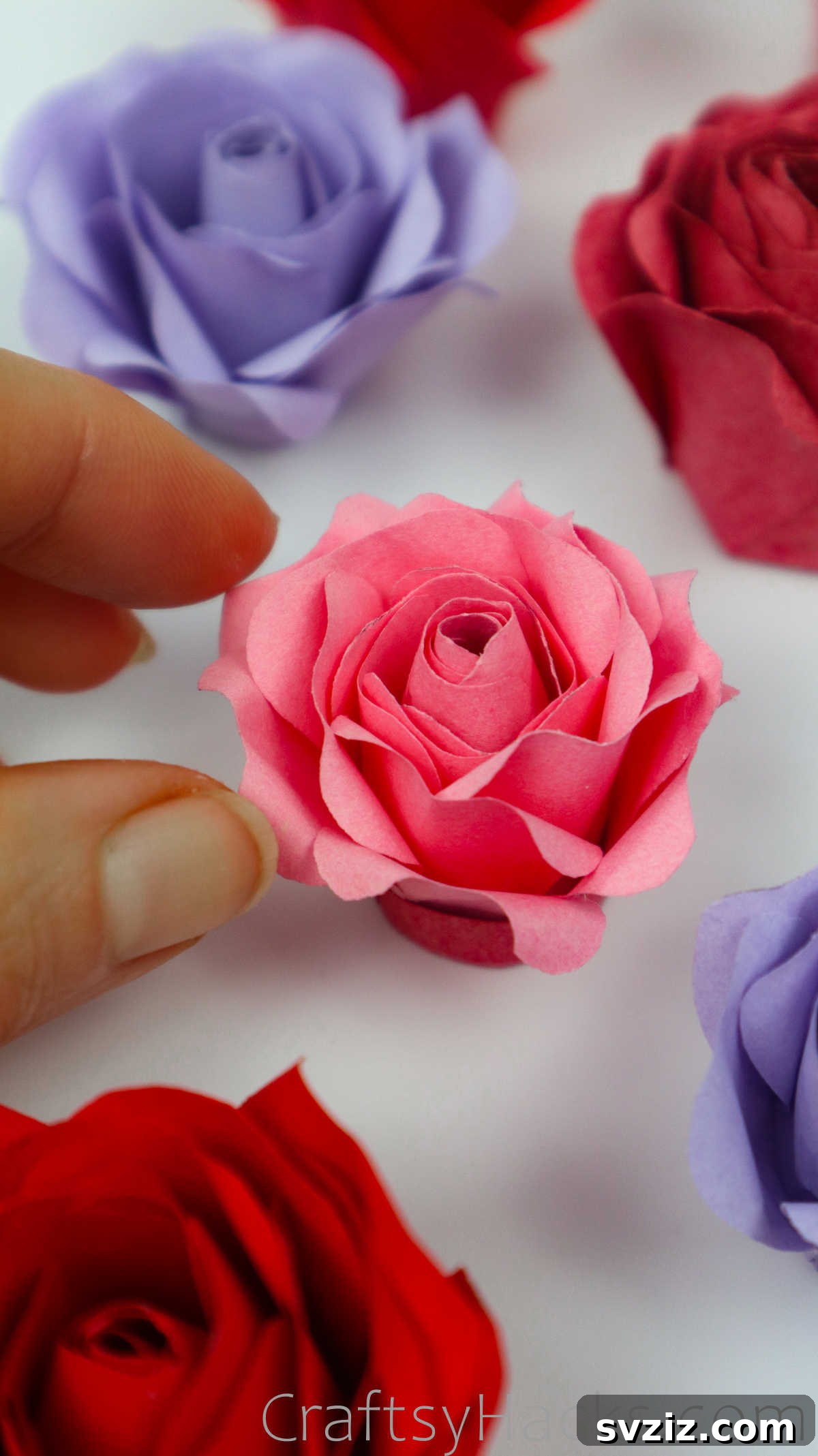 Your Simple Guide to Gorgeous Paper Roses 52 A completed, elegant pink paper rose with delicately curled petals on a dark background