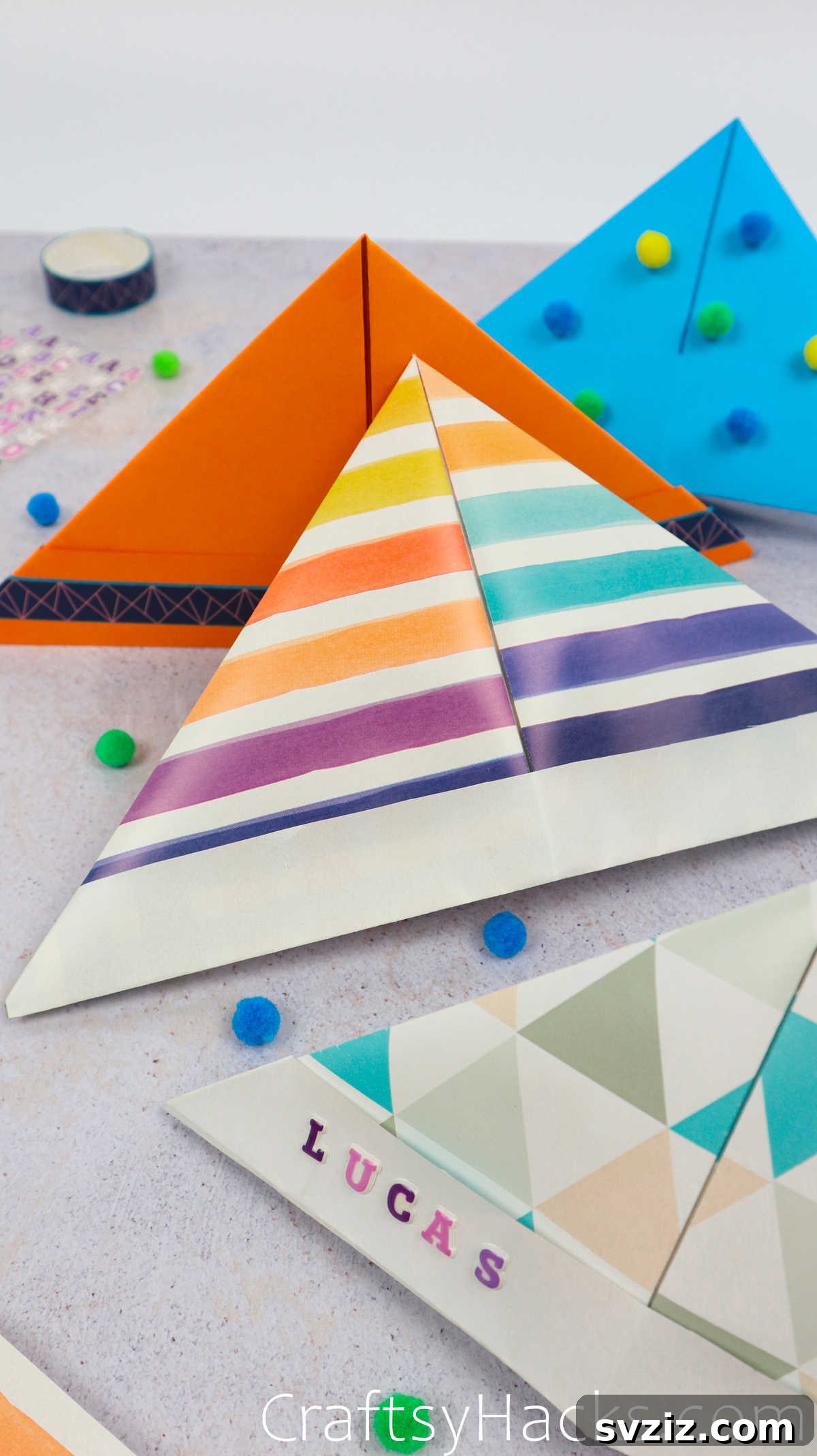 Two completed DIY paper hats, one orange and one blue, on a wooden surface.