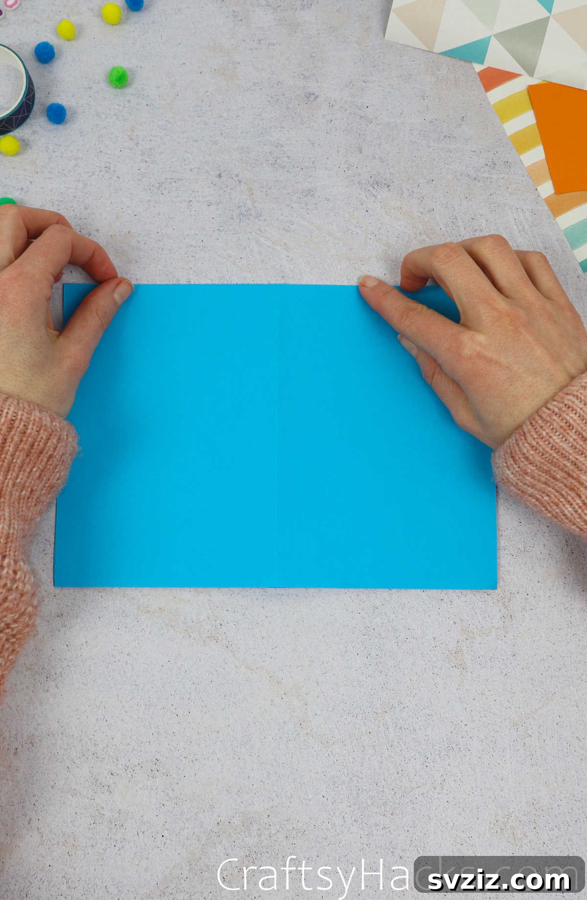 The blue paper folded in half again, with the open edges facing down and a central crease visible.