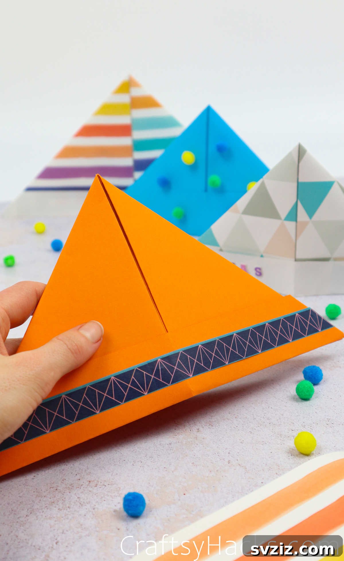 A child's hand holding a vibrant orange DIY paper hat, showing its simple design.