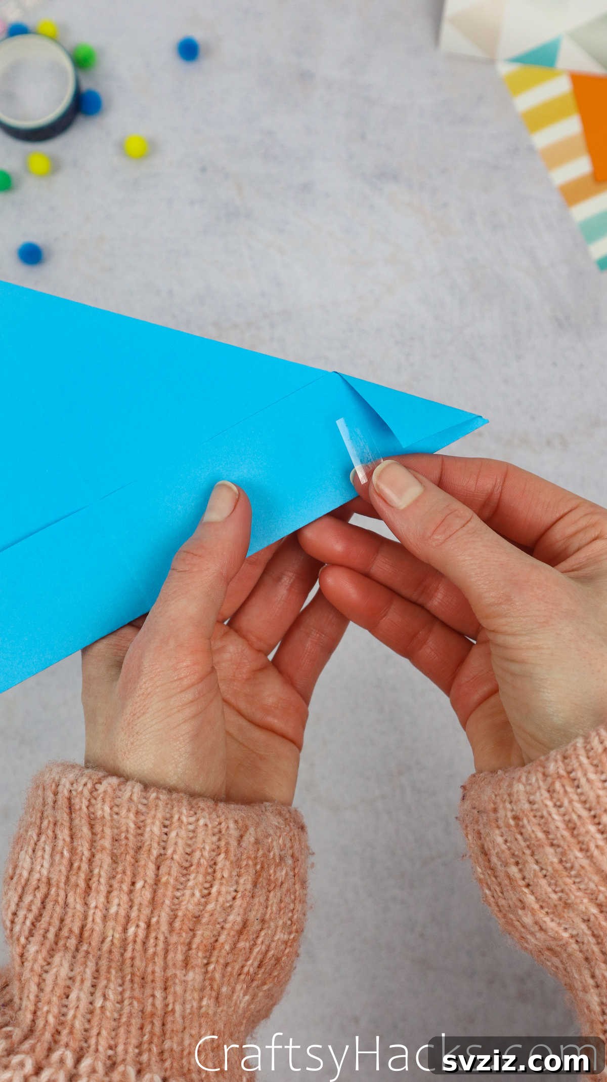 Using tape to secure the folded-in corners of the paper hat, ensuring they stay in place.
