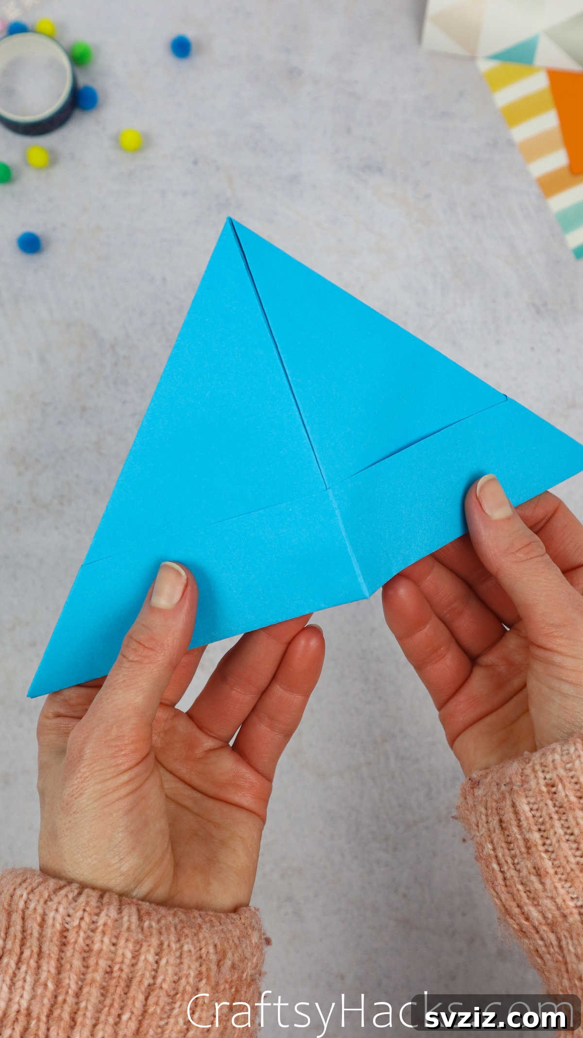 The almost-finished paper hat being gently opened up to reveal its conical shape.