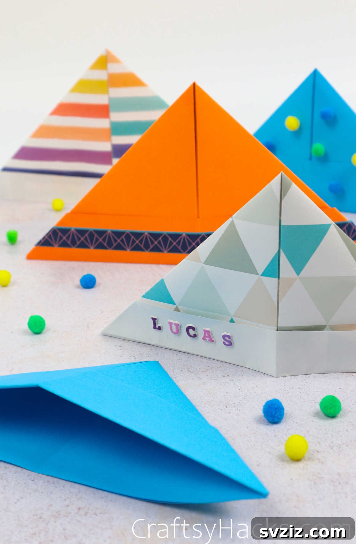 A blue DIY paper hat personalized with a child's name in letter stickers.