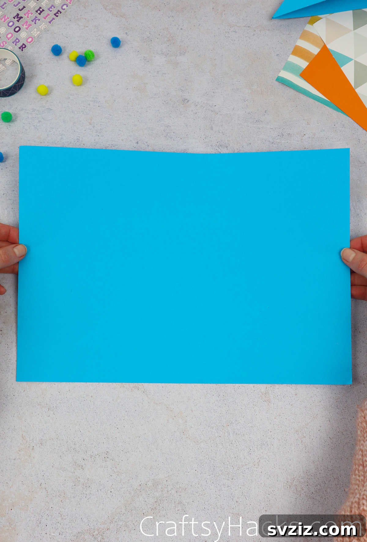 A blue rectangular paper sheet folded in half lengthwise, showing the first crease.