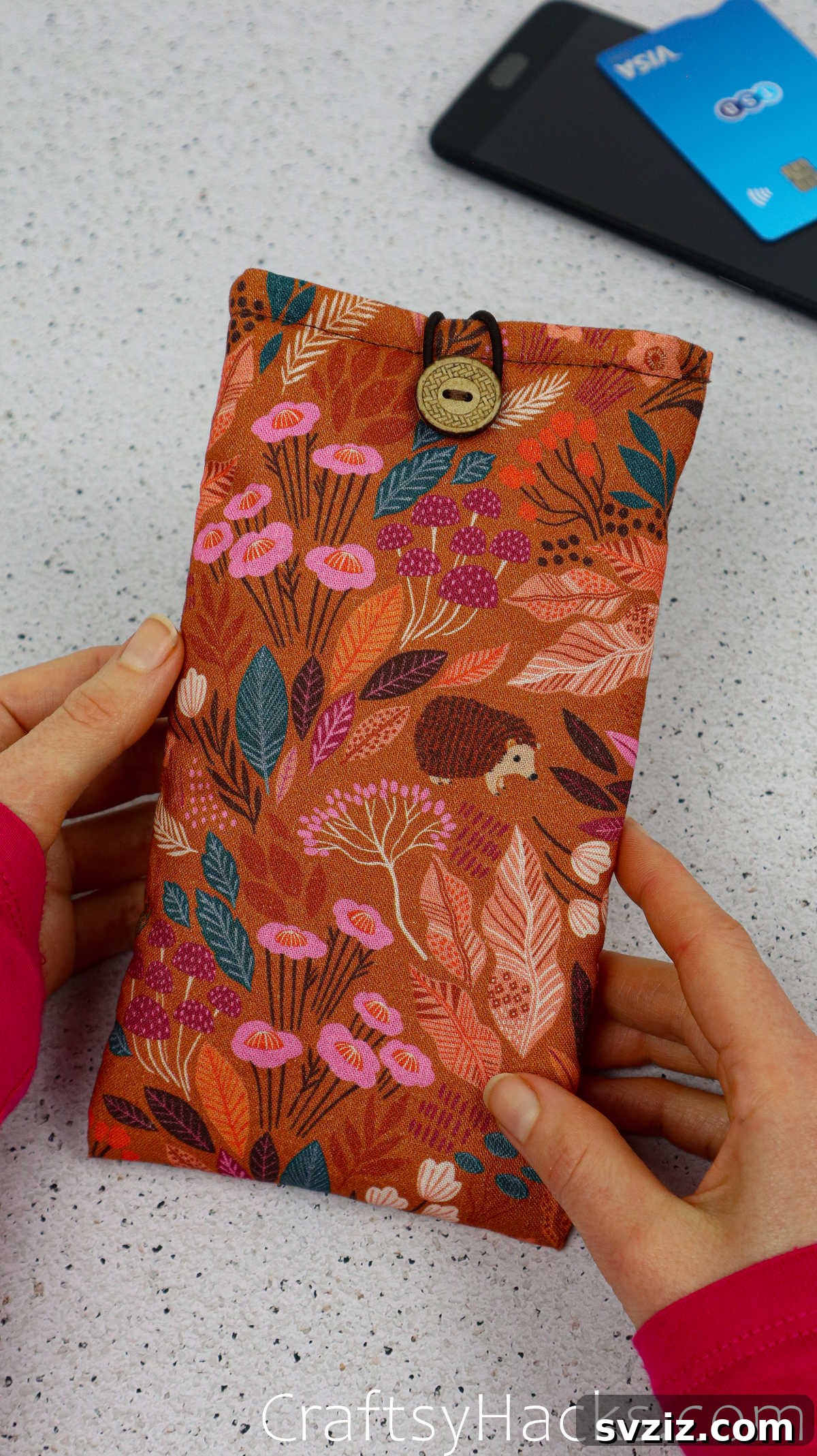 Holding a charming DIY fabric phone case, perfect for adding a personal touch to your device and keeping it safe.