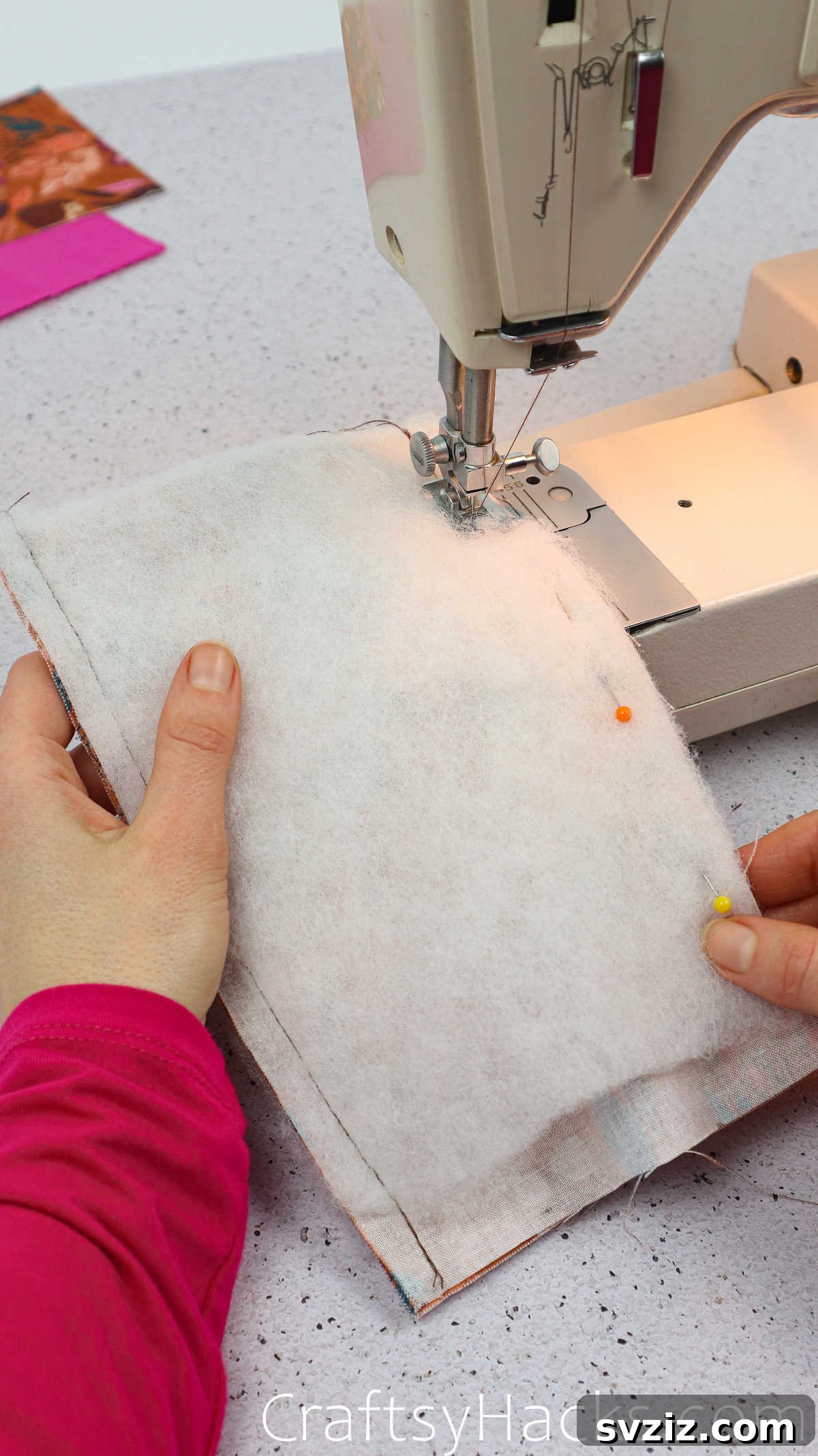 A sewing machine stitching the side of the folded fabric and wadding, creating the initial seam of the phone case.
