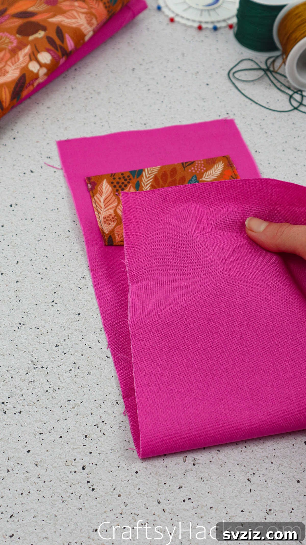 The lining fabric folded in half with the pocket inside, pinned along the raw edges for stitching.