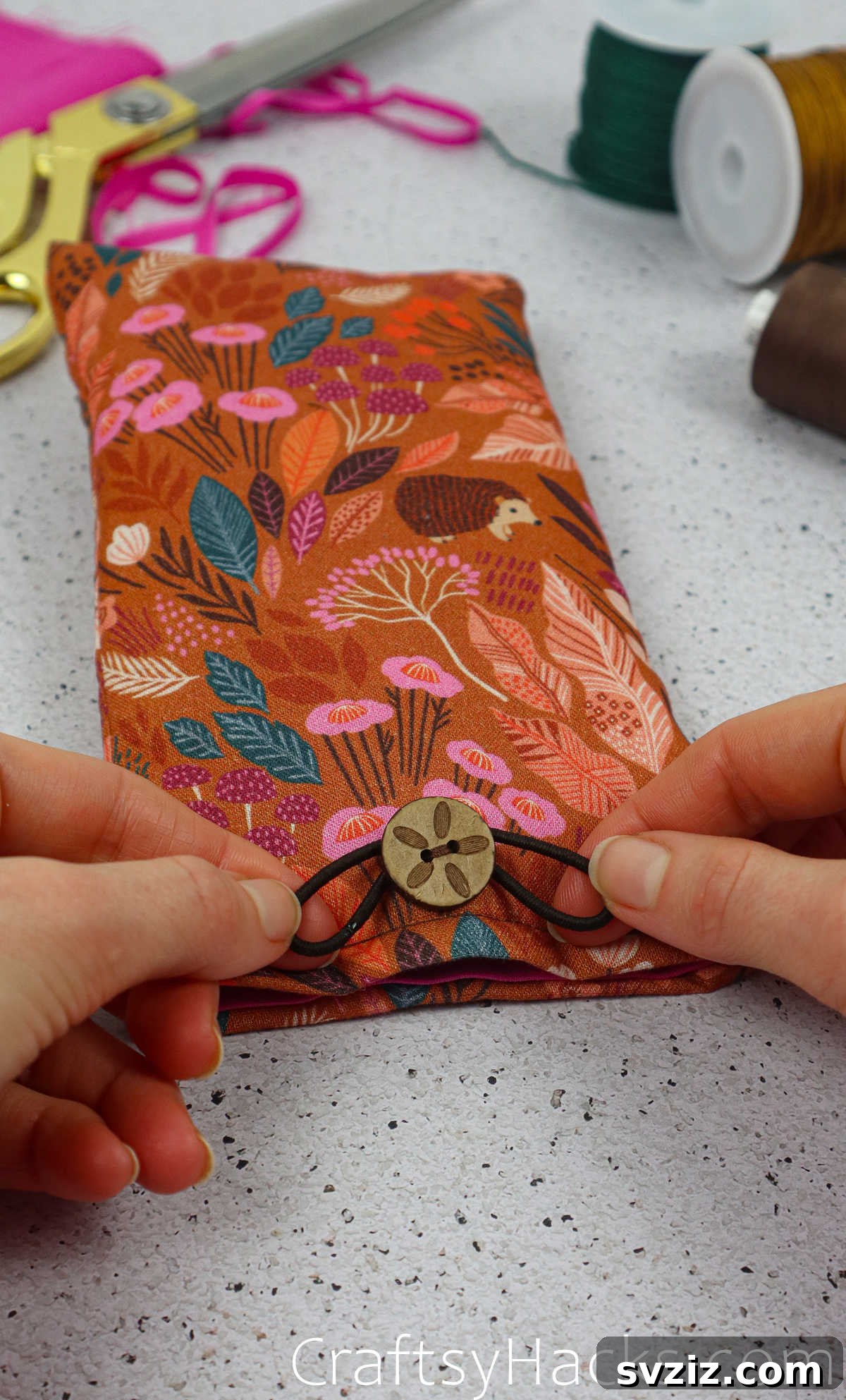 An elastic hair tie wrapped securely around one of the buttons on the fabric phone case.