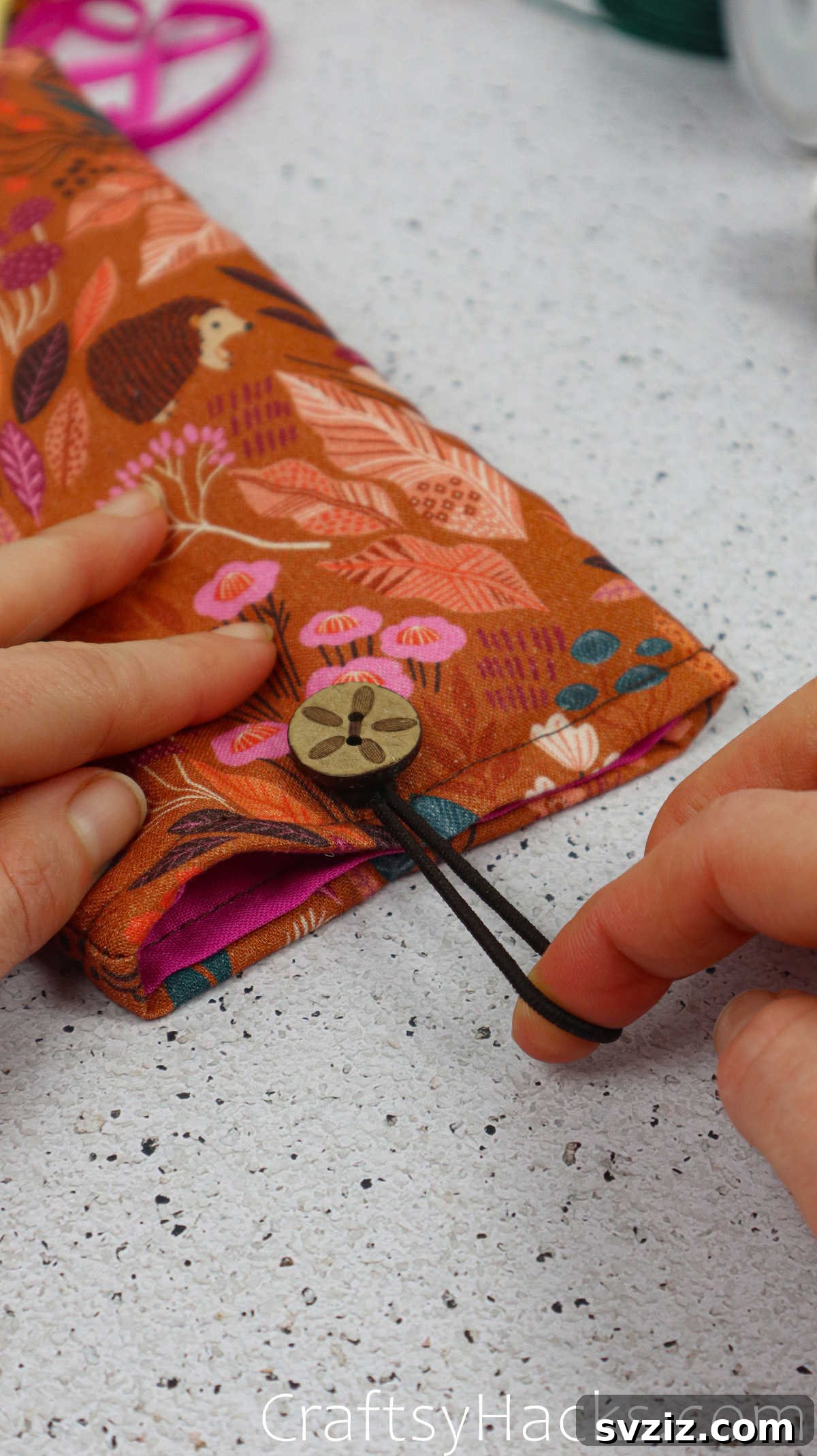 The elastic hair tie being stretched over the phone case opening and hooked onto the second button for closure.