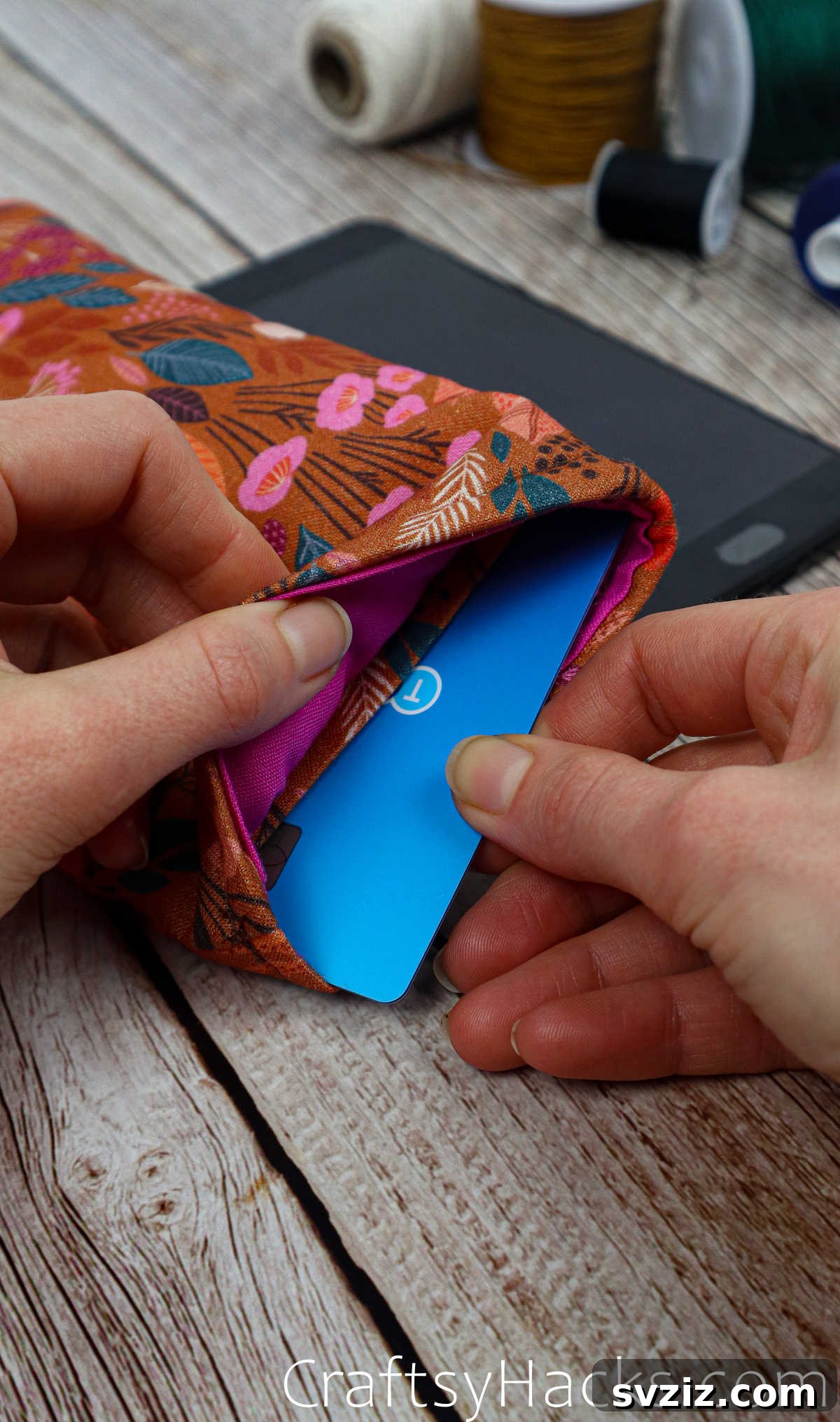 A debit card being slipped into the inner pocket of the fabric phone case, highlighting its practical storage feature.