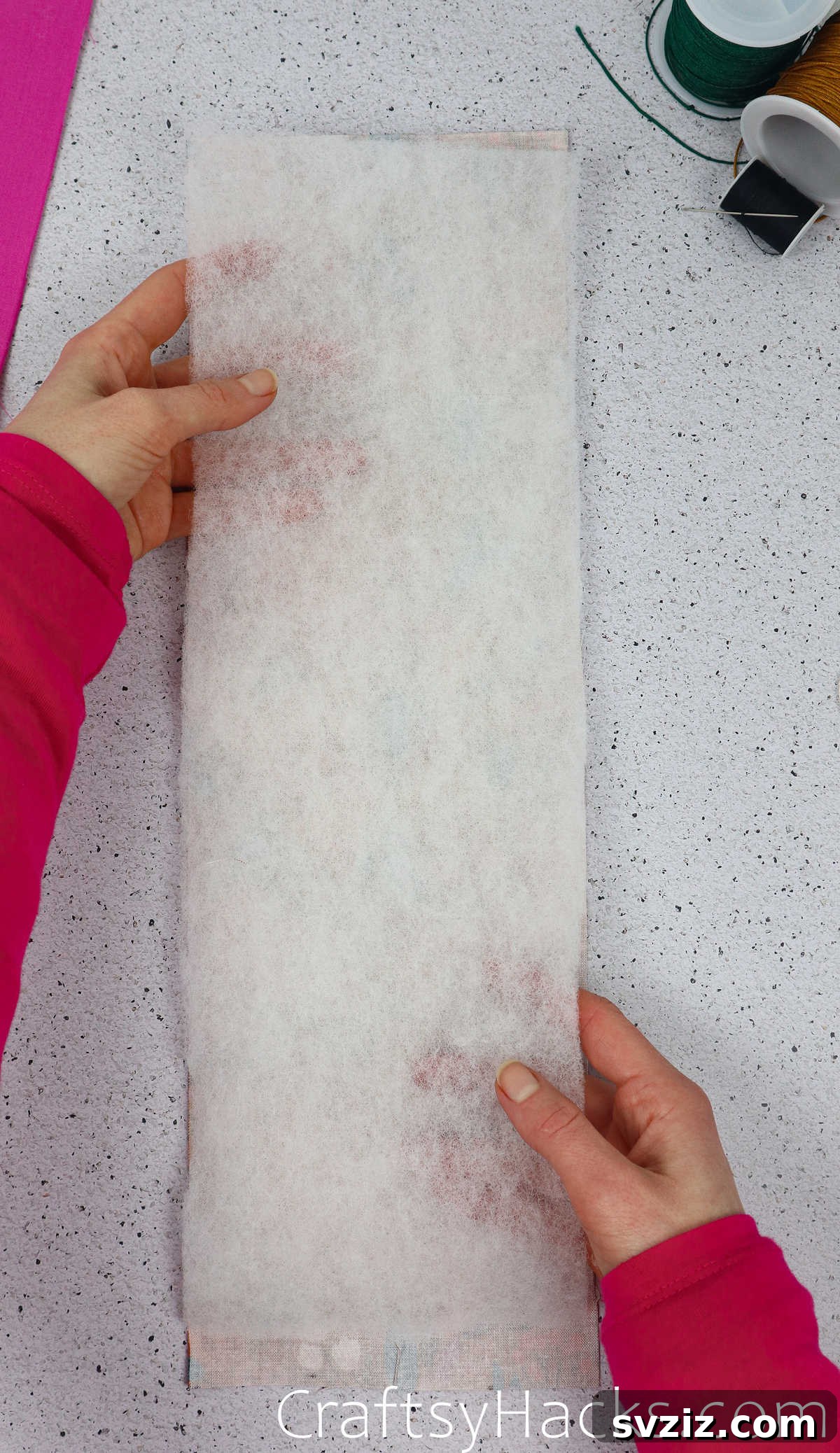 A white wadding piece carefully placed on top of the patterned fabric, ensuring the half-inch margin at the edges.