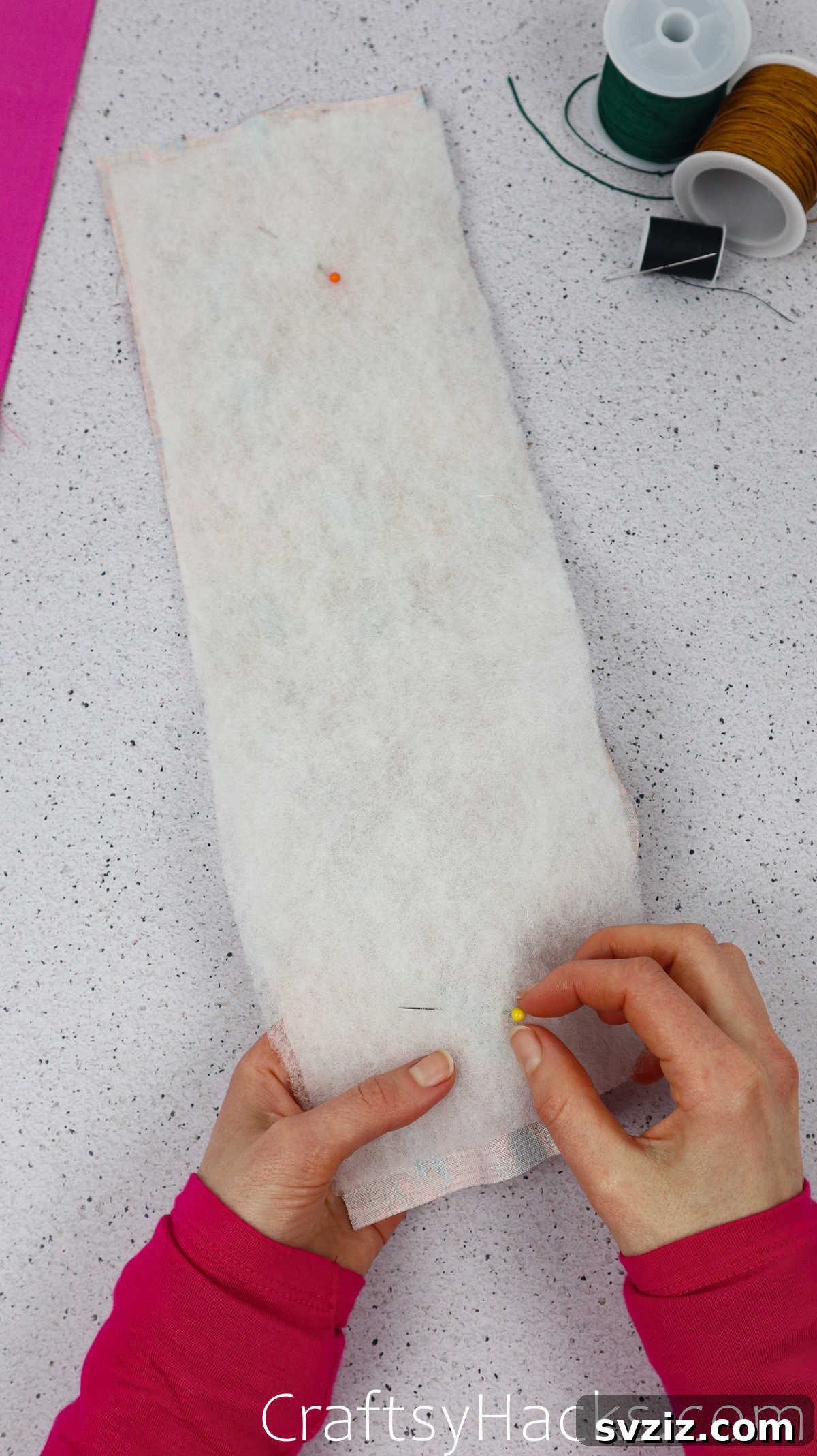 Sewing pins securing the wadding to the main fabric, preparing it for the next step of folding and stitching.