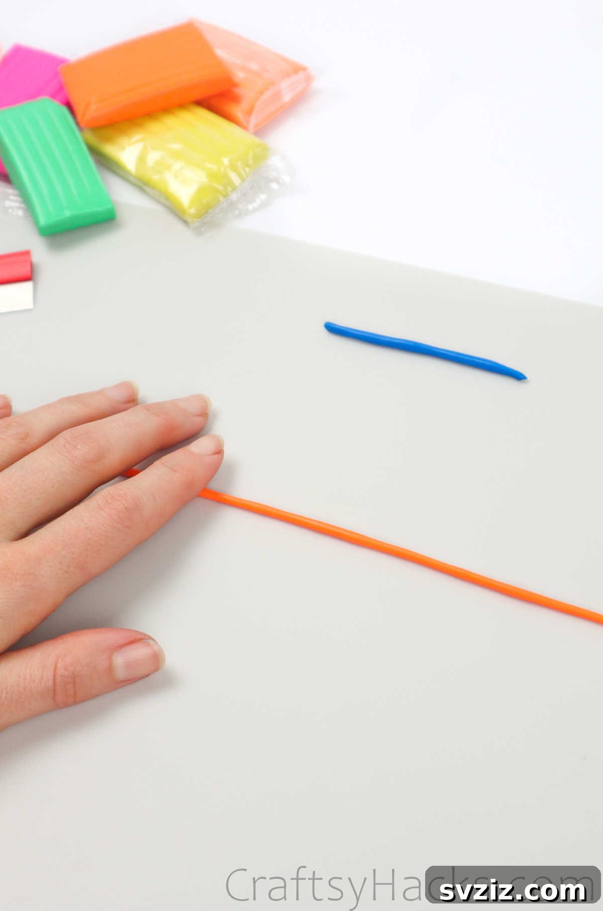 Crafting Your Own Clay Rings Effortlessly 13 A hand rolling out a vibrant orange polymer clay strand on a clean white surface