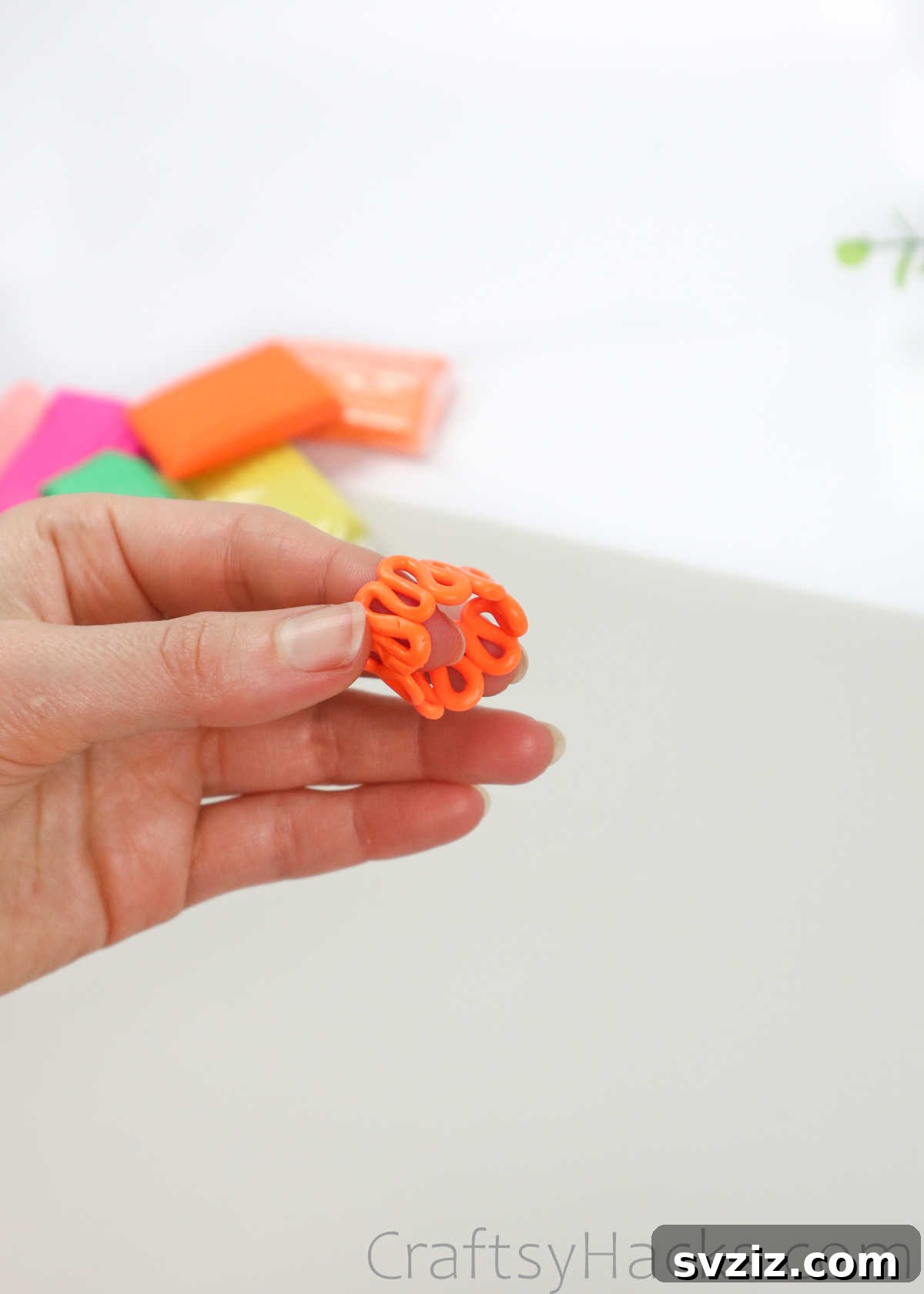 Crafting Your Own Clay Rings Effortlessly 16 A hand shaping a squiggly orange polymer clay ring, joining the ends to form a closed loop
