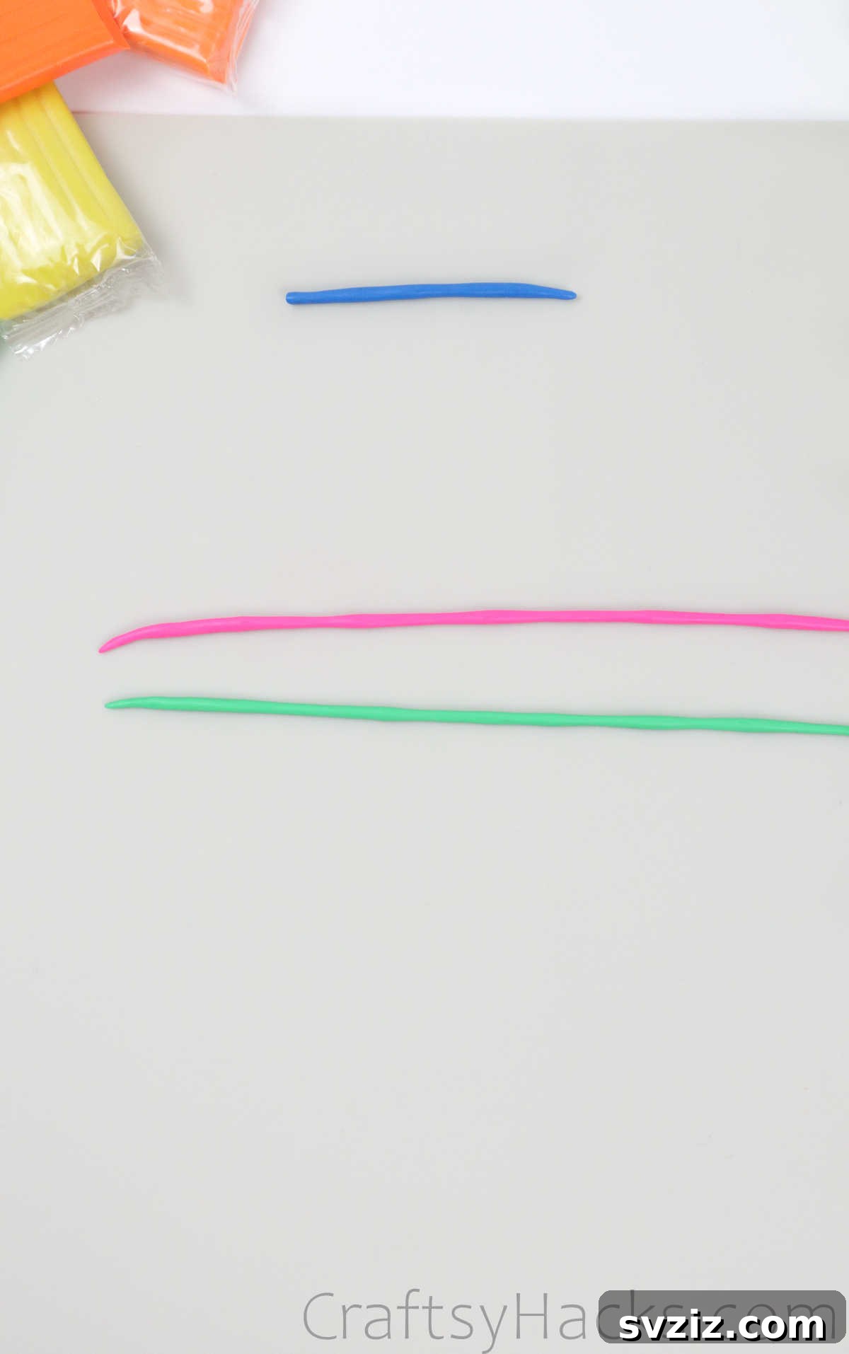 Crafting Your Own Clay Rings Effortlessly 17 Two thin strands of polymer clay, one pink and one green, laid side by side on a surface