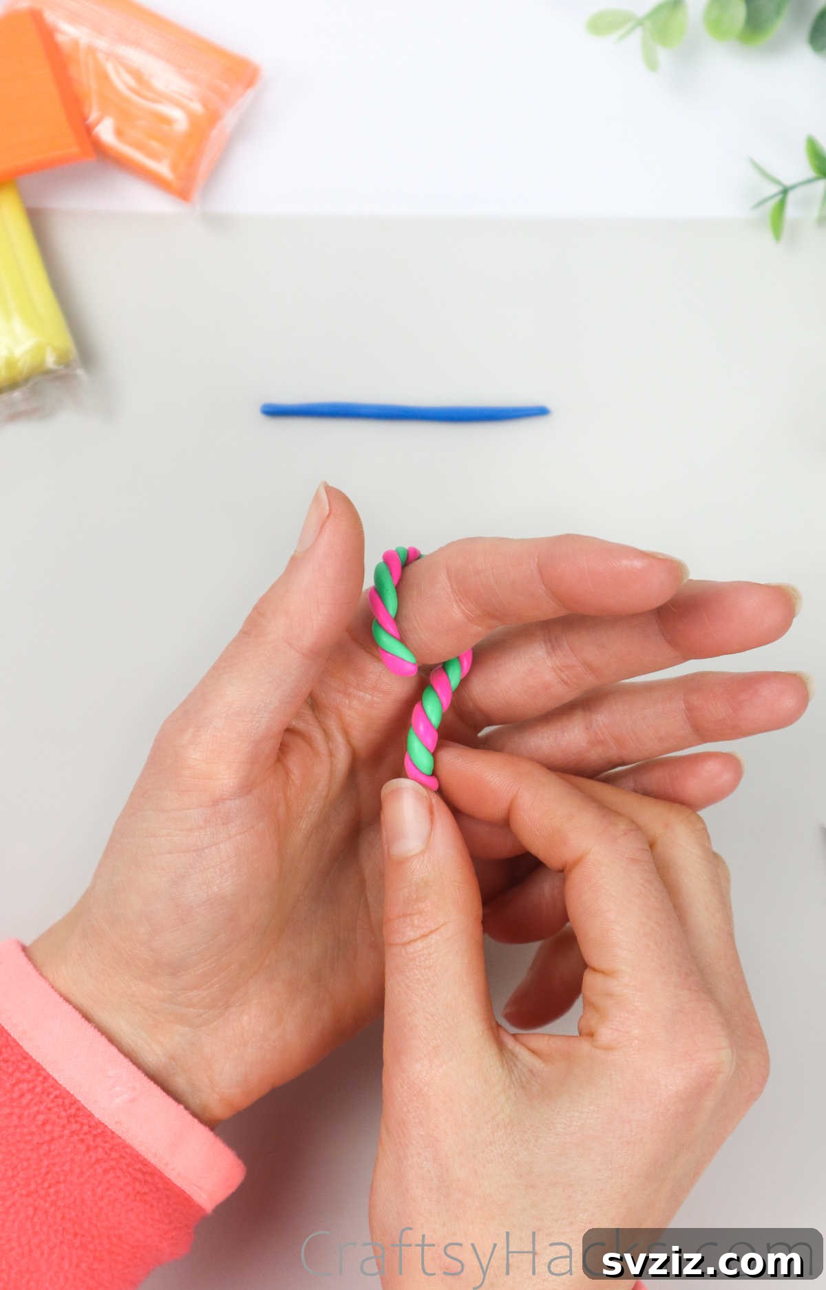 Crafting Your Own Clay Rings Effortlessly 19 A twisted pink and green polymer clay strand being wrapped around a finger for size measurement