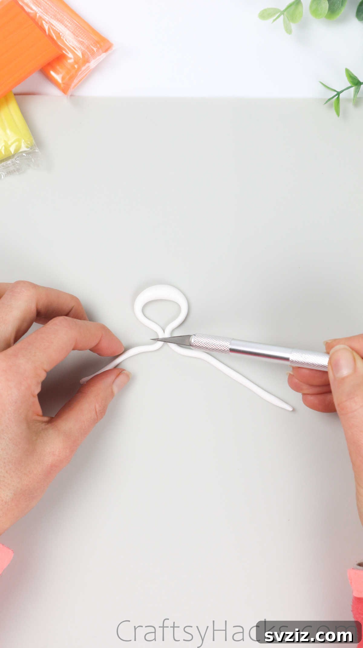 Crafting Your Own Clay Rings Effortlessly 22 A craft knife cutting the ends of the white polymer clay strand with a central bump, sizing it for a ring